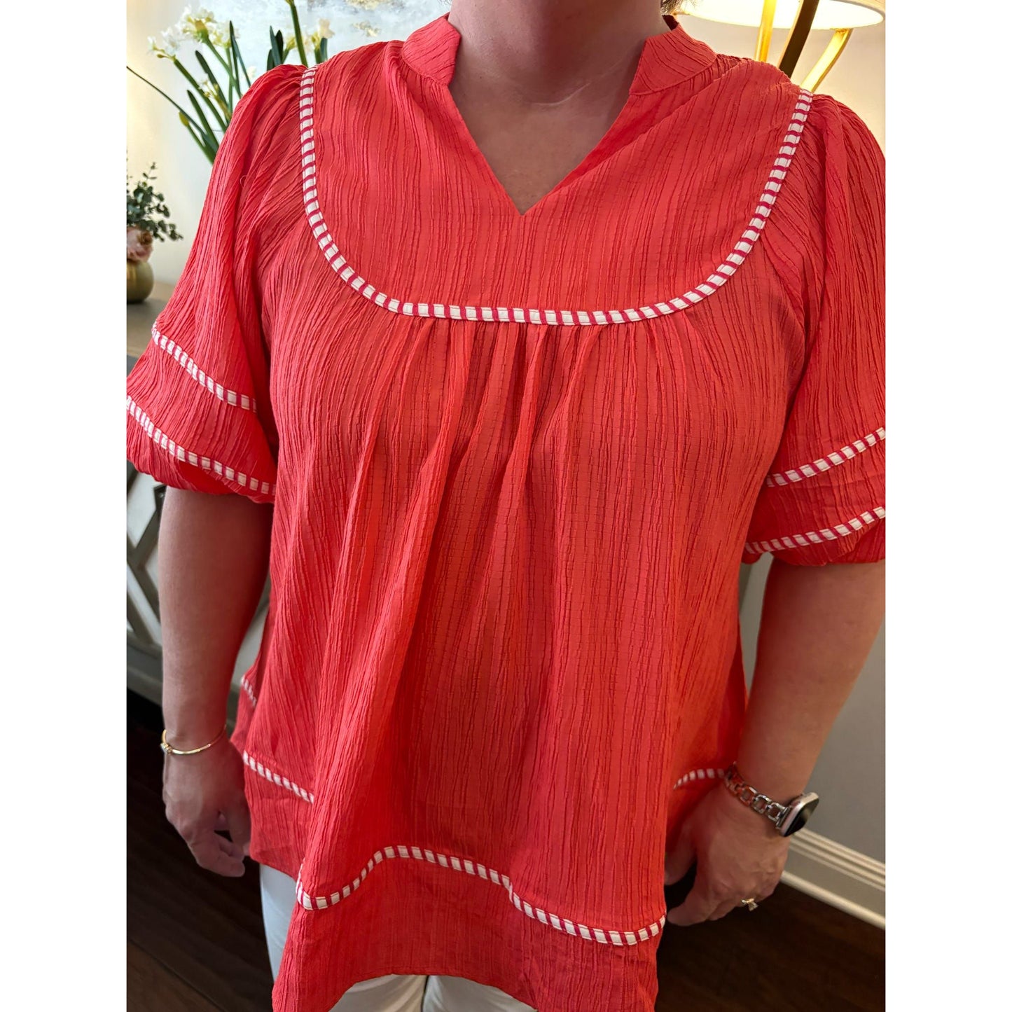 Red blouse with white trim worn by a person indoors.