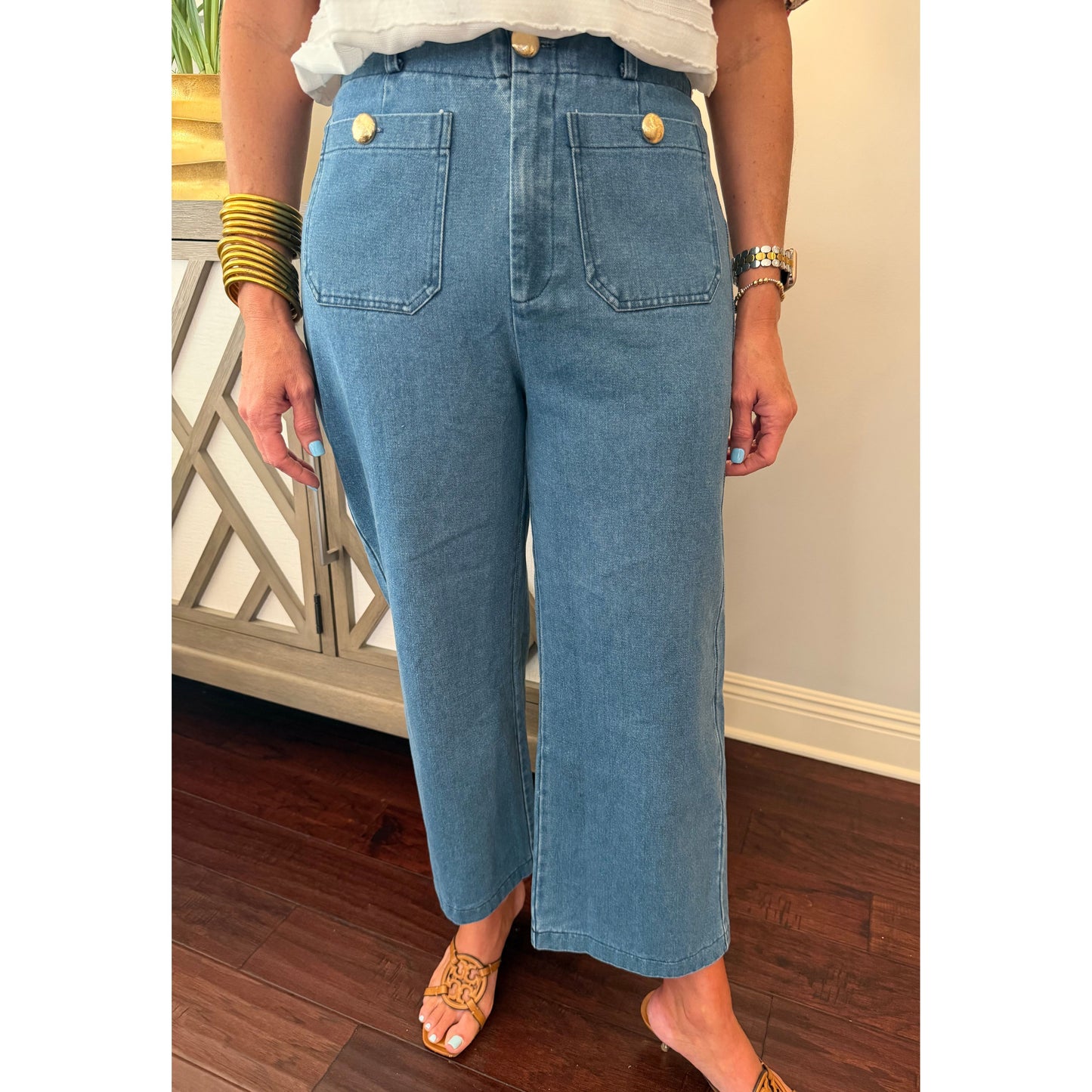 Person wearing blue jeans with gold buttons indoors.