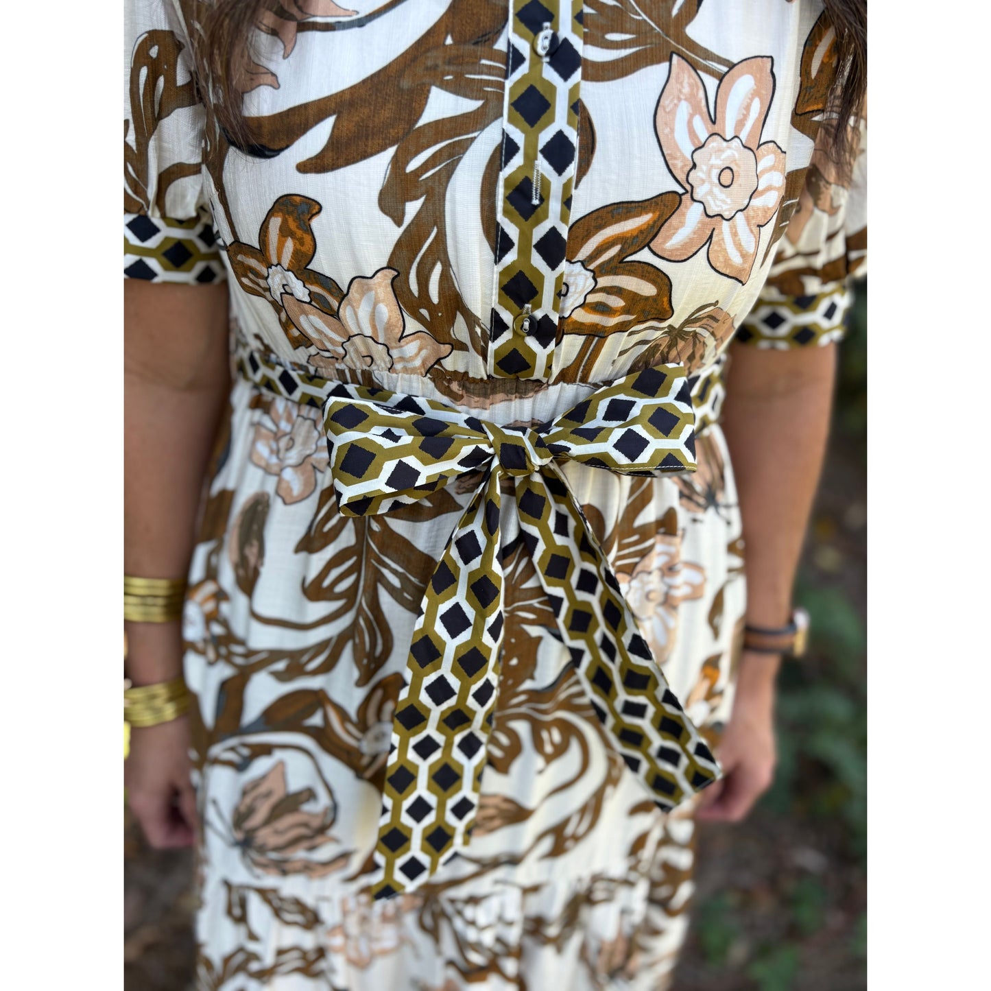Close-up of a person wearing a patterned dress with a tie waist.