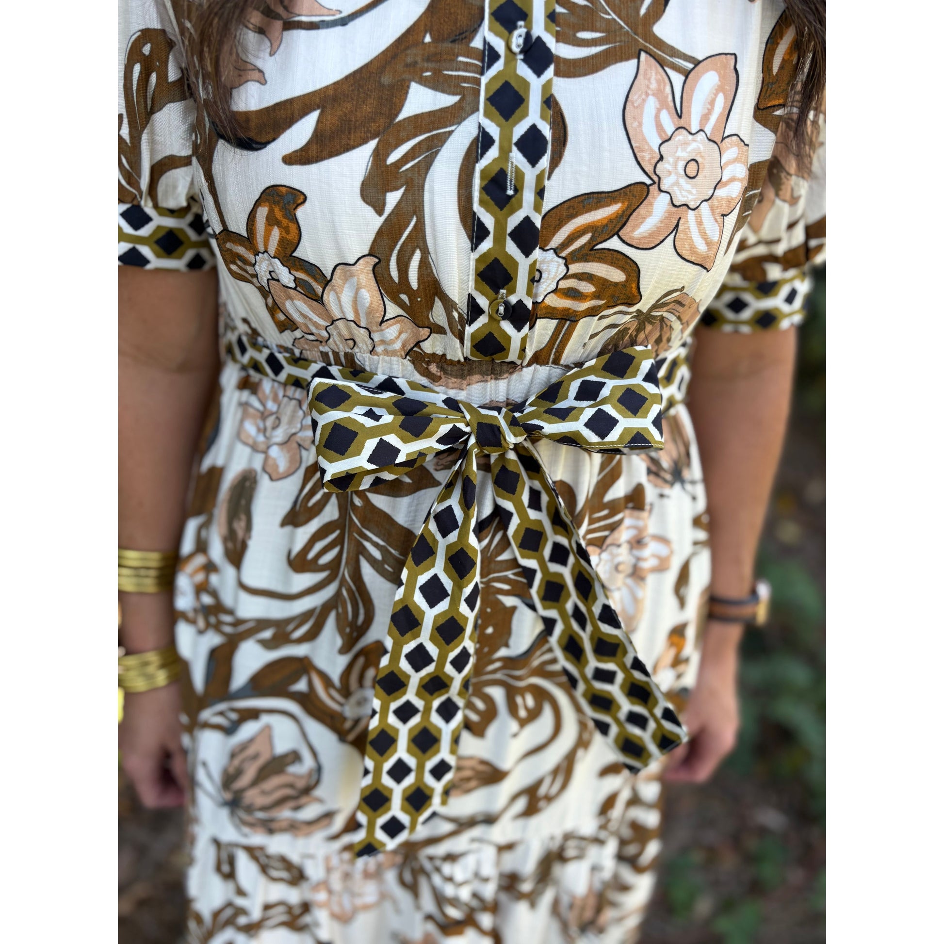 Close-up of a person wearing a patterned dress with a tie waist.