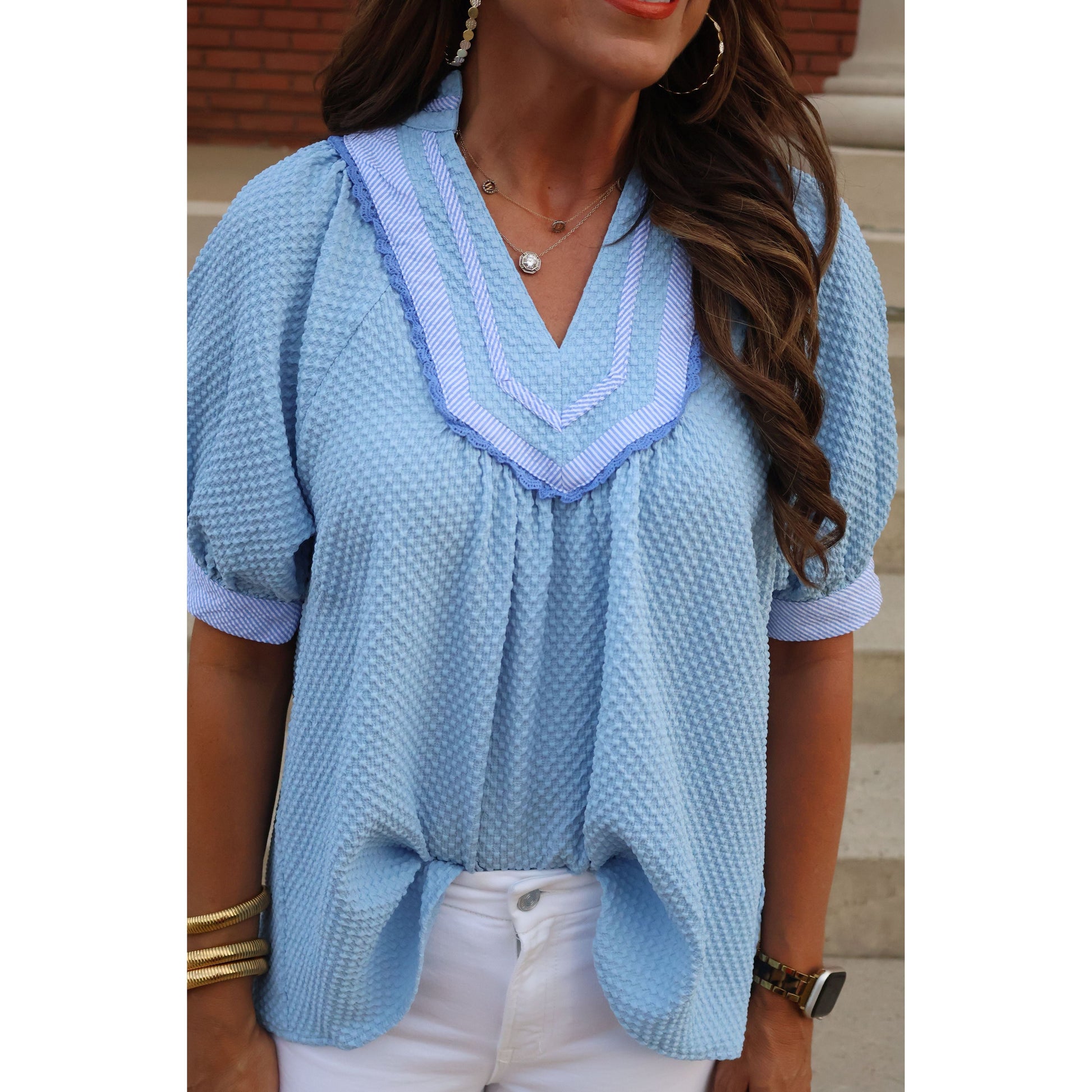 Person wearing a light blue textured jacket with a white shirt underneath.