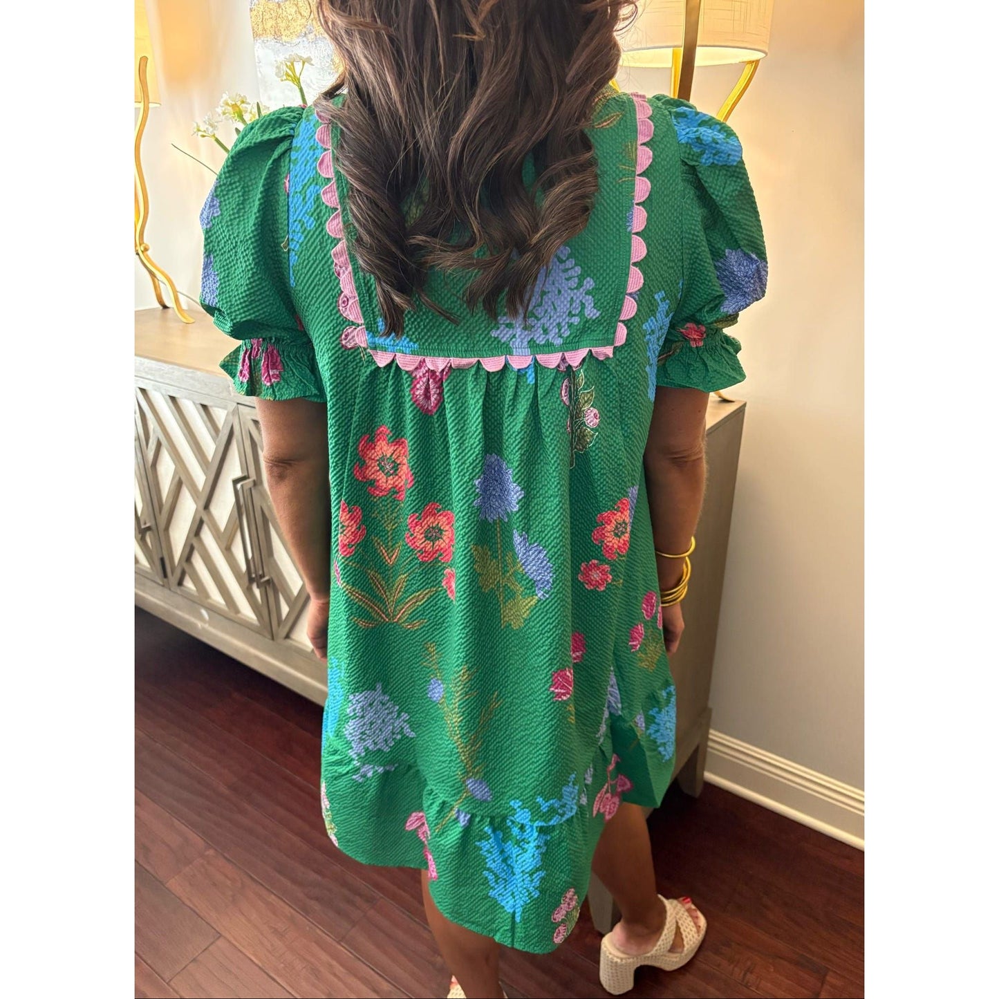 Person wearing a green floral dress standing indoors.