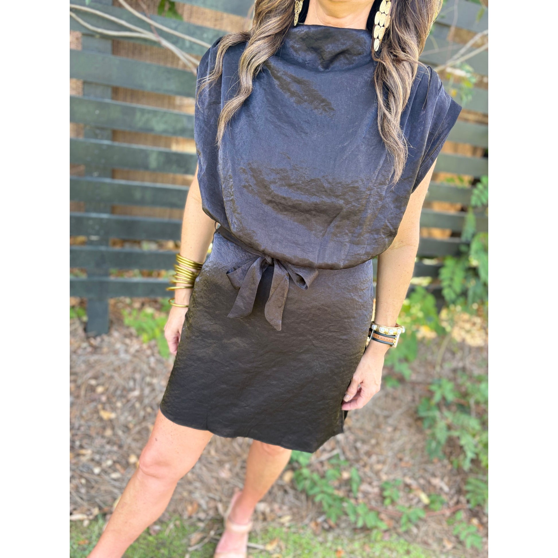 Woman wearing a black dress with a tie detail in an outdoor setting