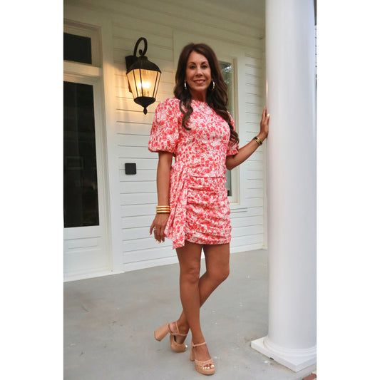 Woman in a pink floral dress standing on a porch