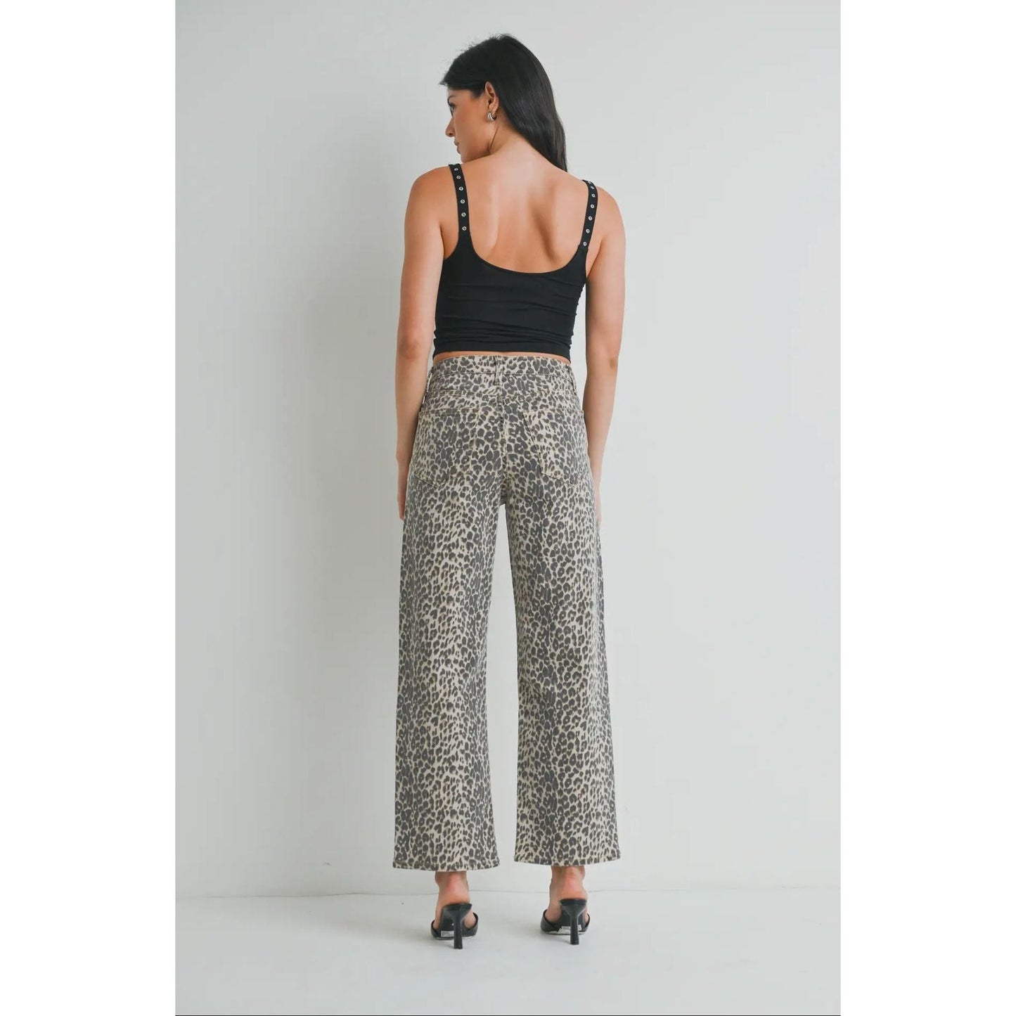 Woman wearing a black tank top and patterned pants on a plain background