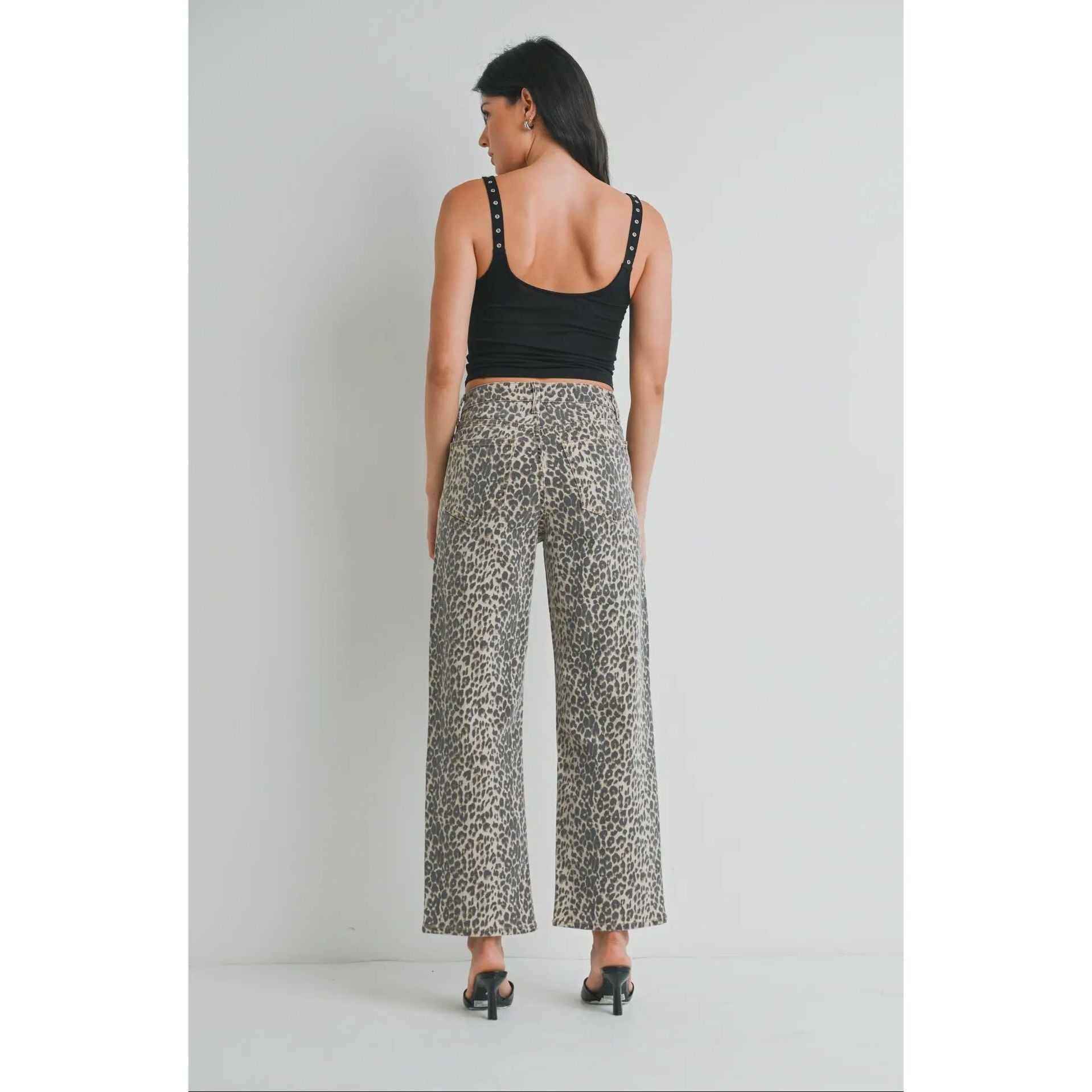 Woman wearing a black tank top and patterned pants on a plain background