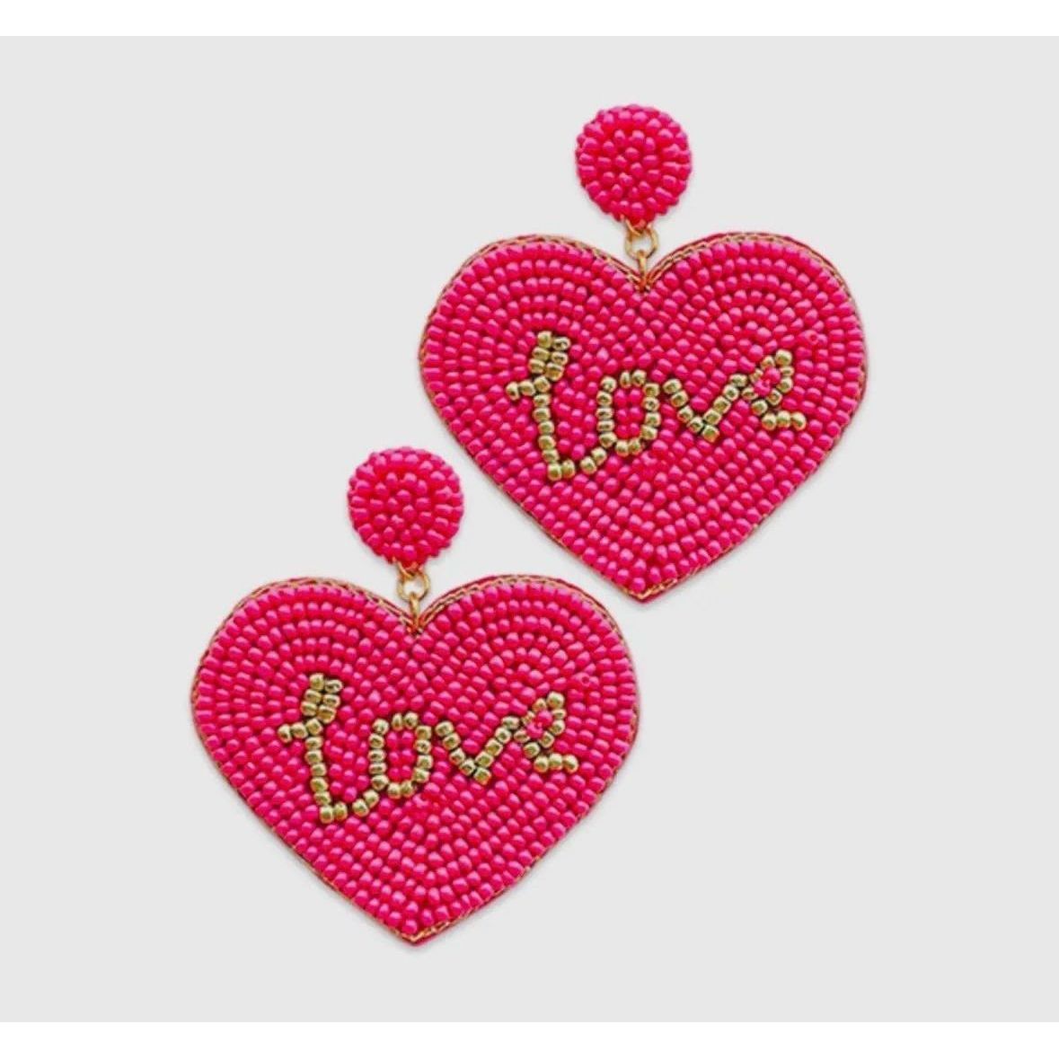 Heart-shaped pink beaded earrings with 'love' text on a light gray background