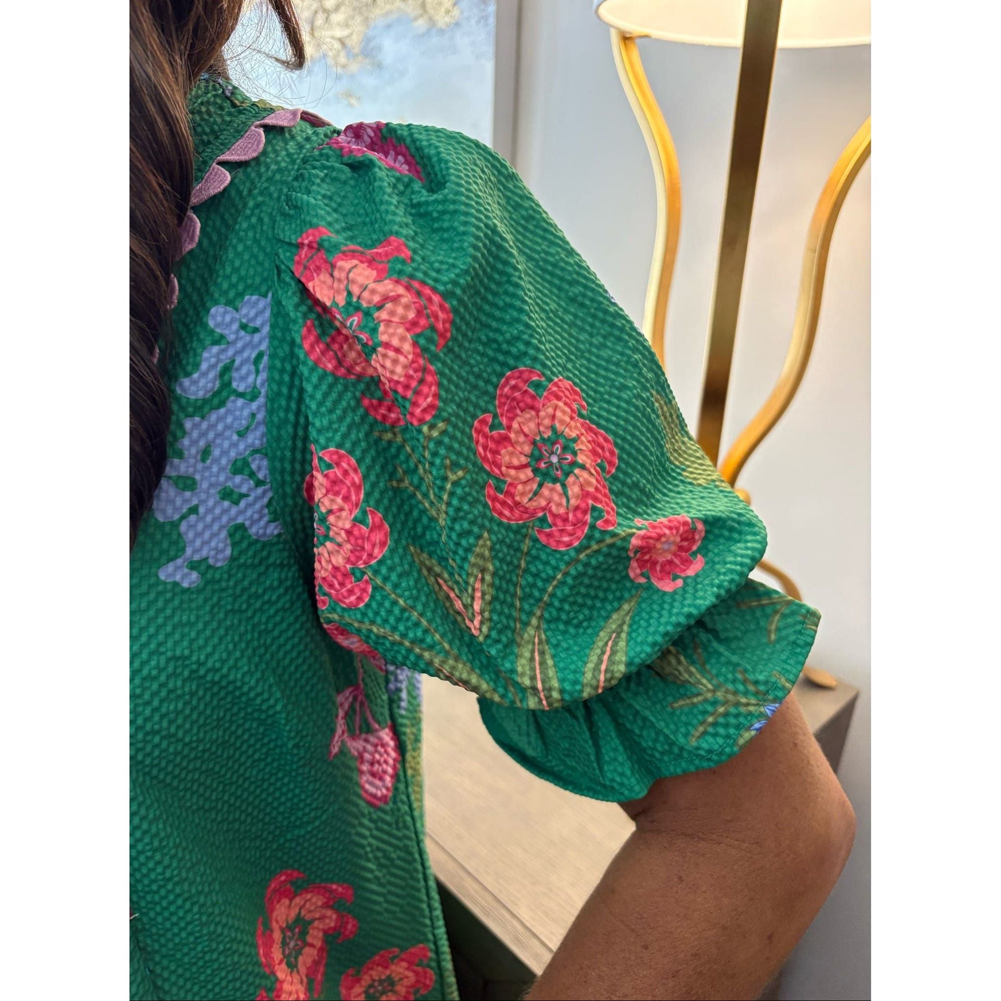 Green floral-patterned fabric draped over a person with a blurred indoor background