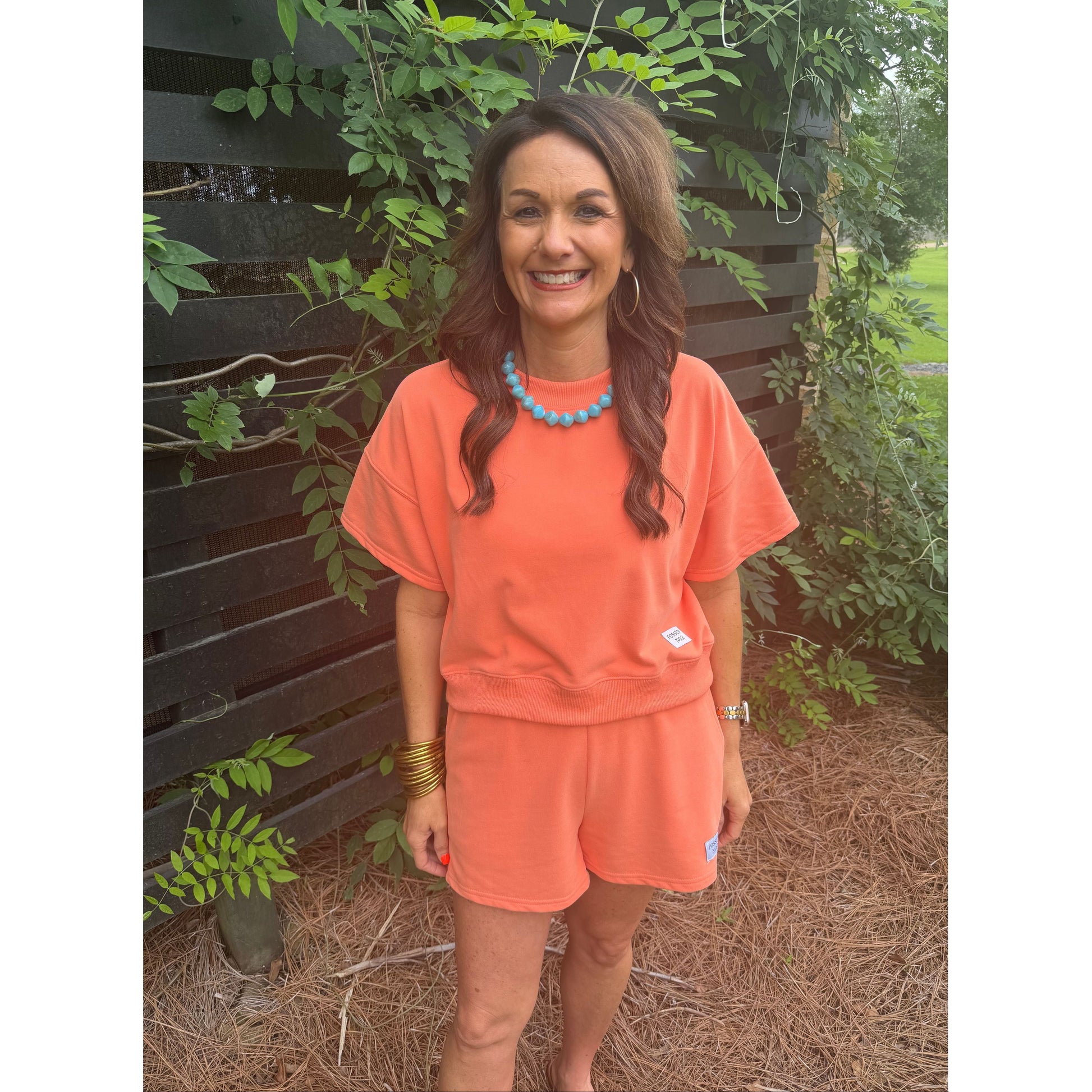 Person wearing an orange outfit with a plant background
