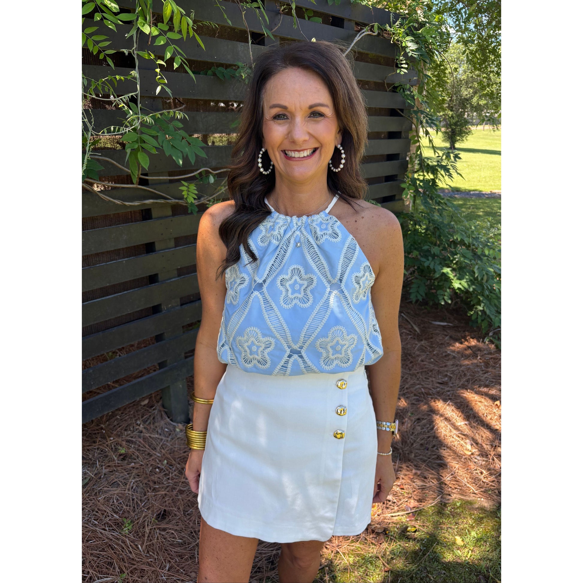 Woman wearing a blue patterned top and white shorts outdoors
