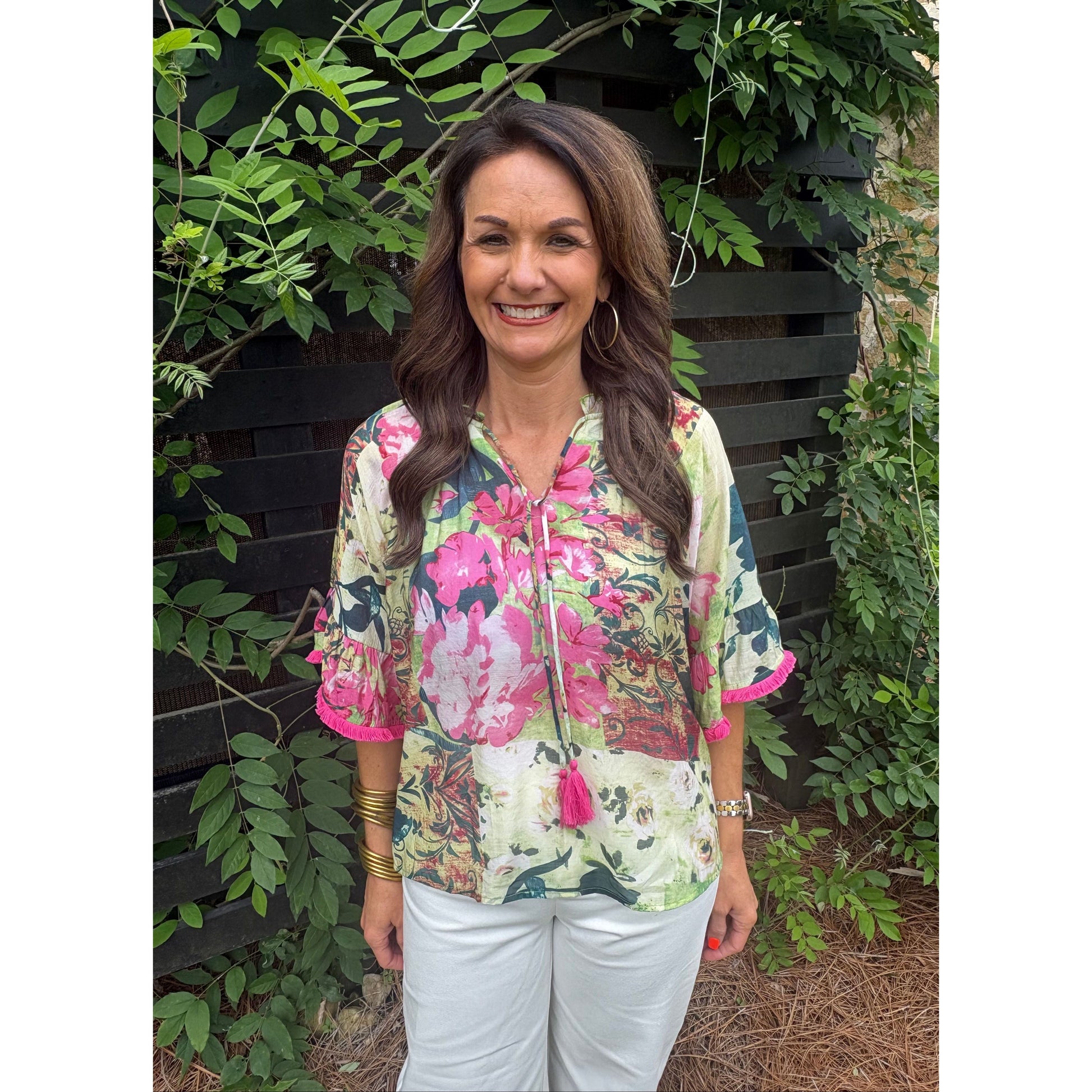 Woman wearing a floral jacket standing among green plants