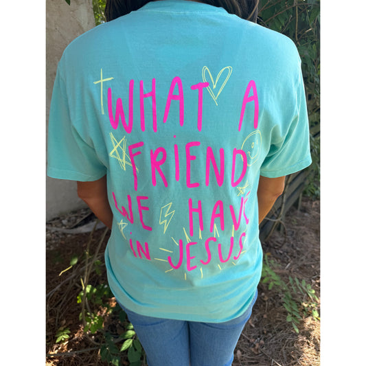 Person wearing a light blue t-shirt with pink text 'What a friend we have in Jesus' outdoors.