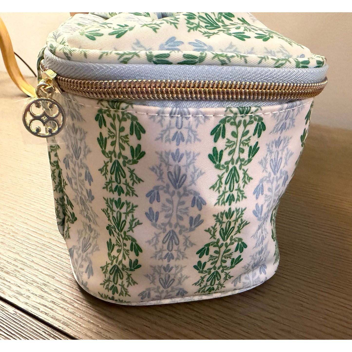 Small fabric pouch with green floral pattern on a wooden surface