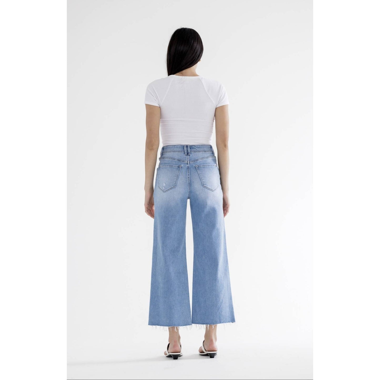 Person wearing light blue jeans and a white top on a white background