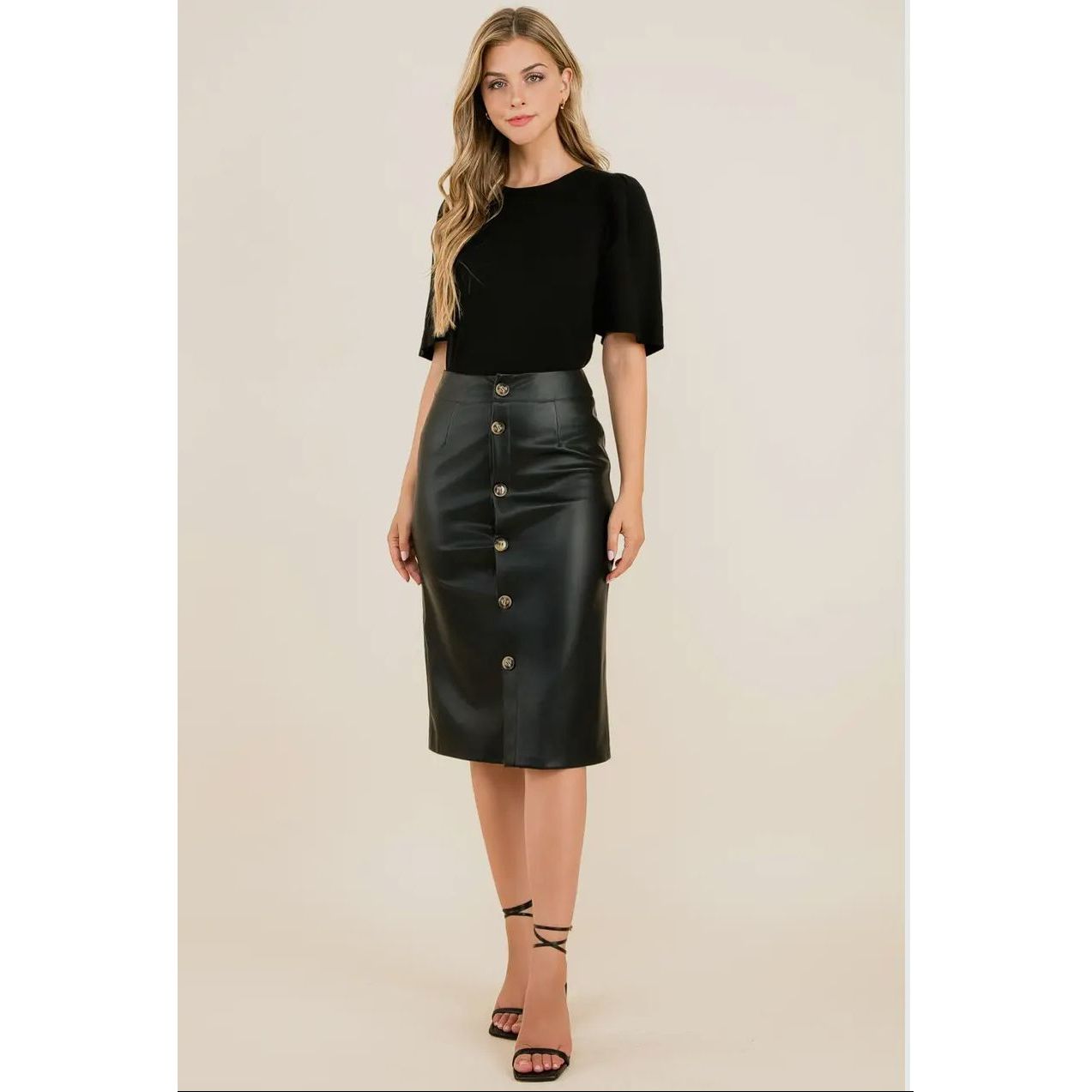 Woman wearing a black top and leather skirt on a beige background