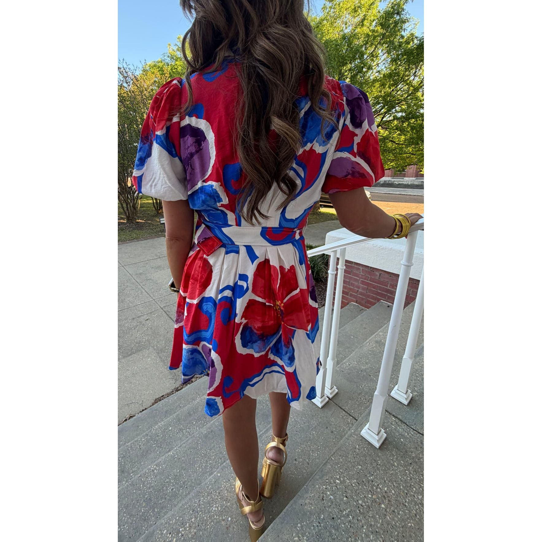 Woman in a colorful dress walking outdoors on a sunny day.