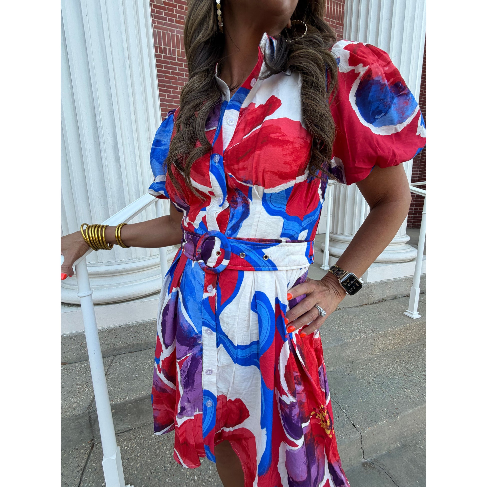 Person wearing a colorful dress with red, blue, and white patterns on a street.