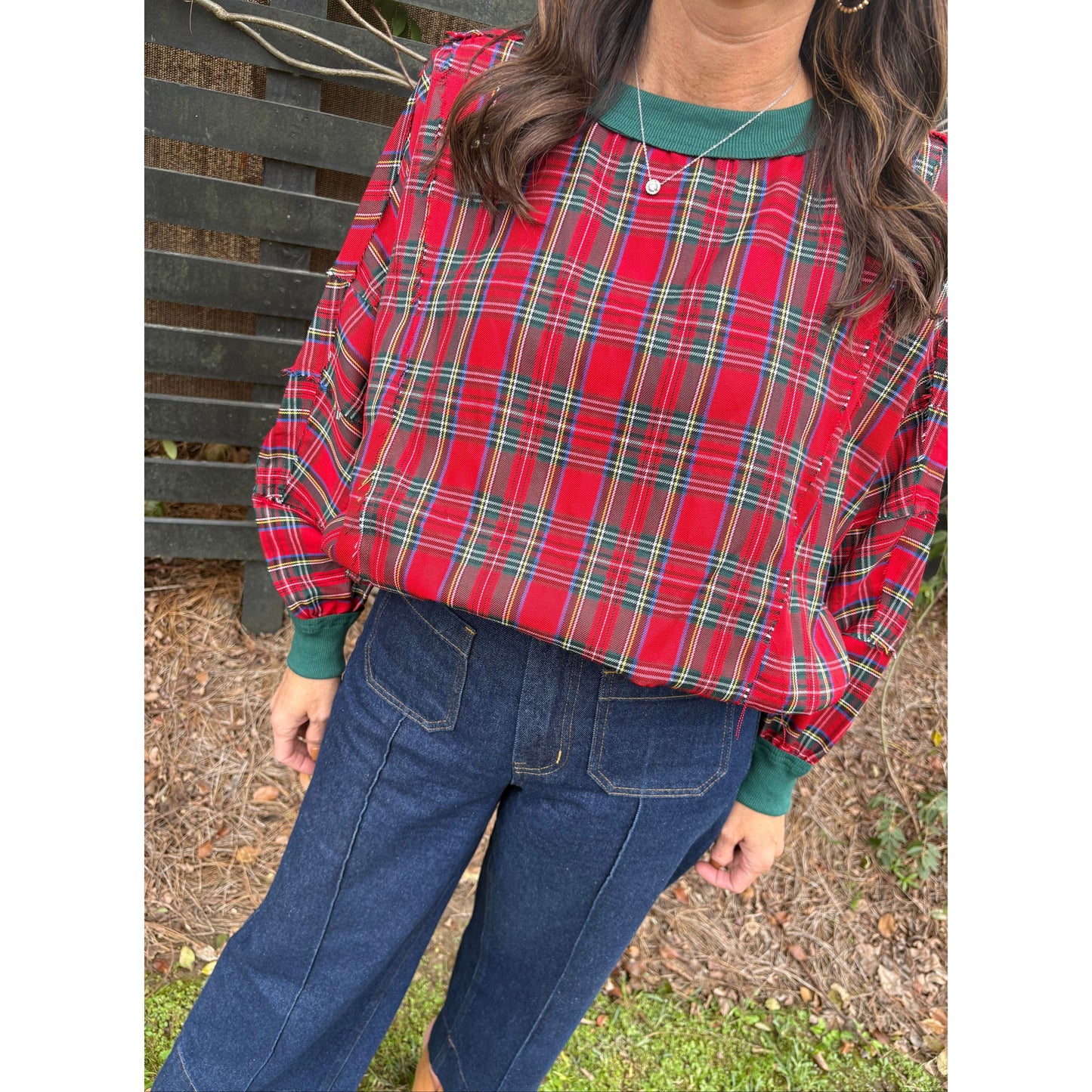 Person wearing a red plaid jacket outdoors on a bench.