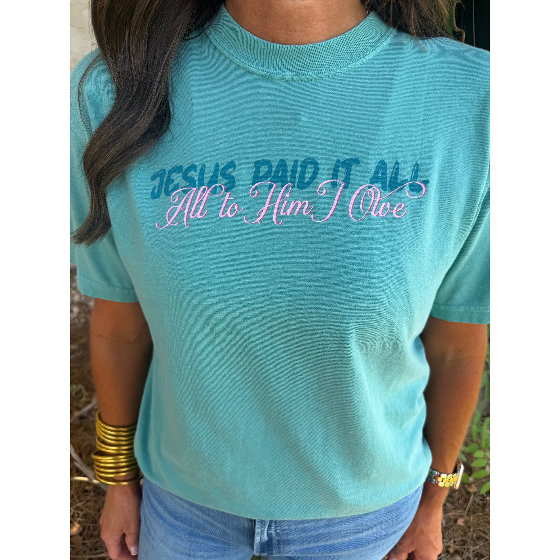 Light blue t-shirt with text design worn by a person outdoors