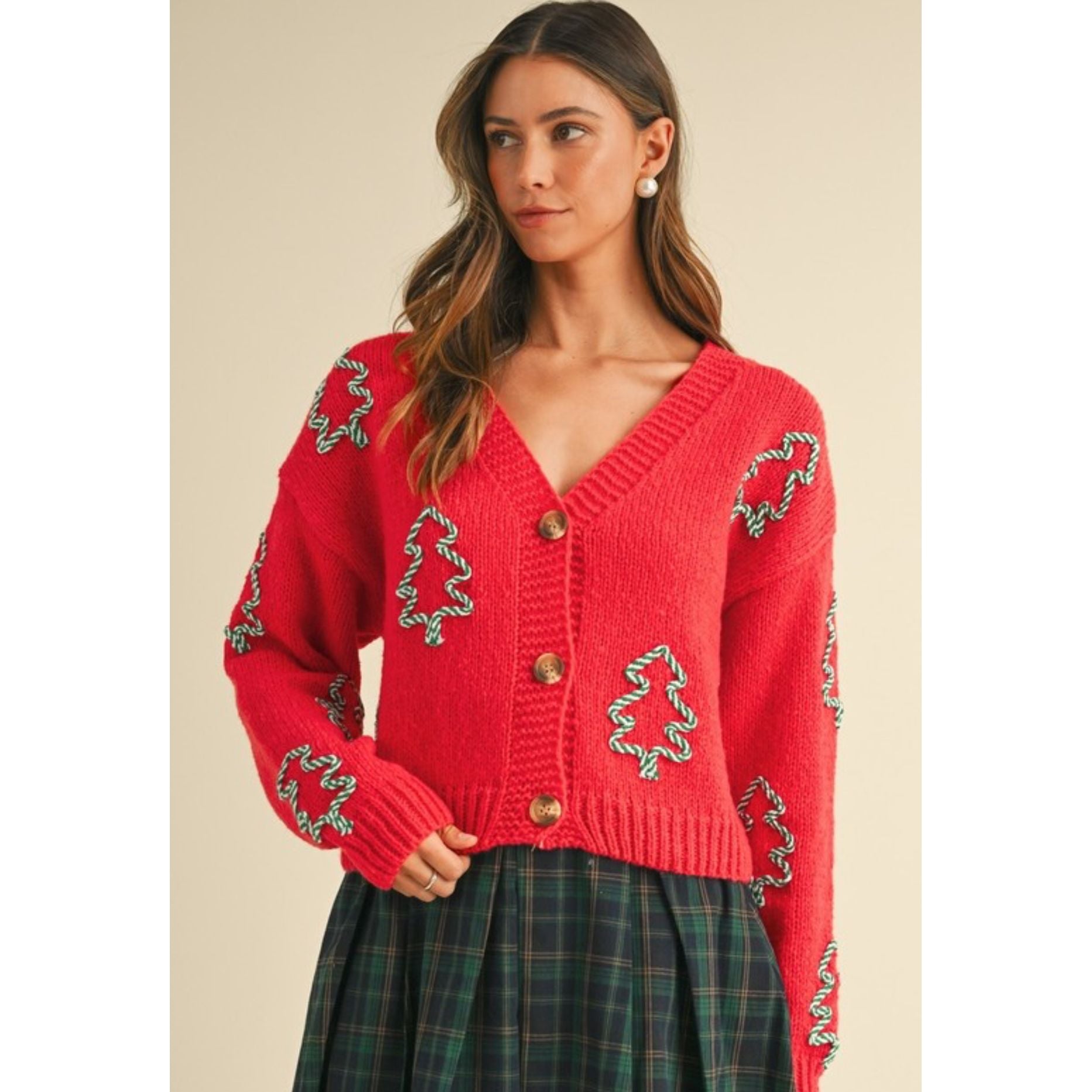 Woman wearing a red knitted cardigan with decorative patterns on a beige background