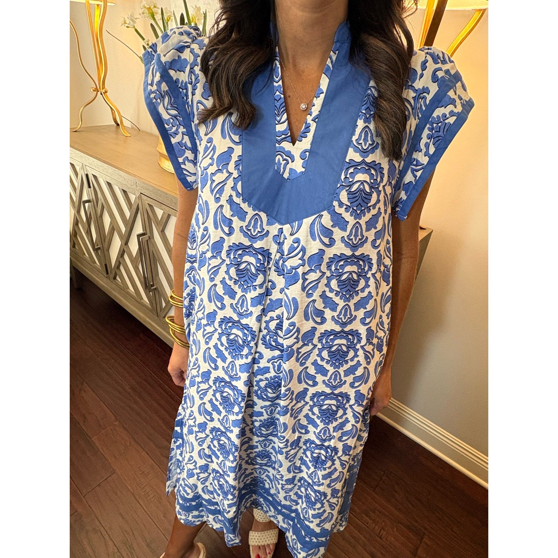 Woman wearing a blue and white patterned dress indoors.