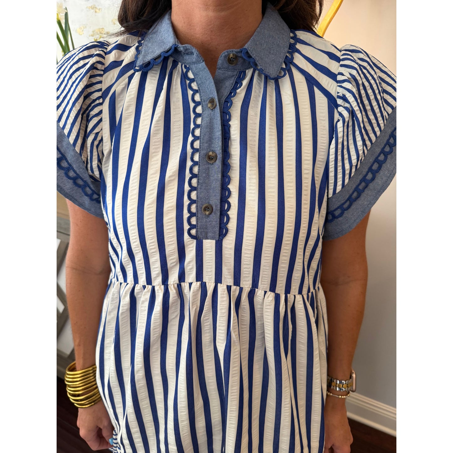 Person wearing a blue and white striped shirt with denim collar and cuffs.