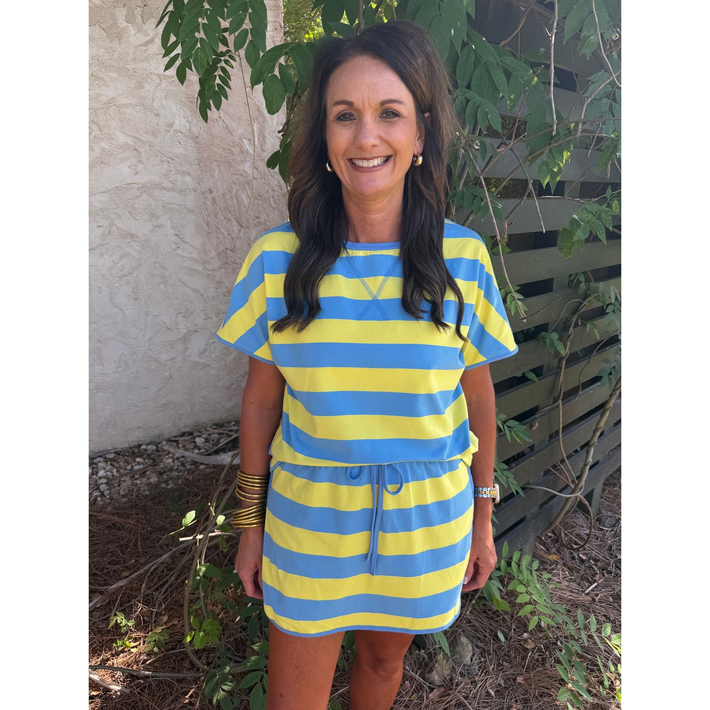 Woman wearing a blue and yellow striped dress standing outdoors.