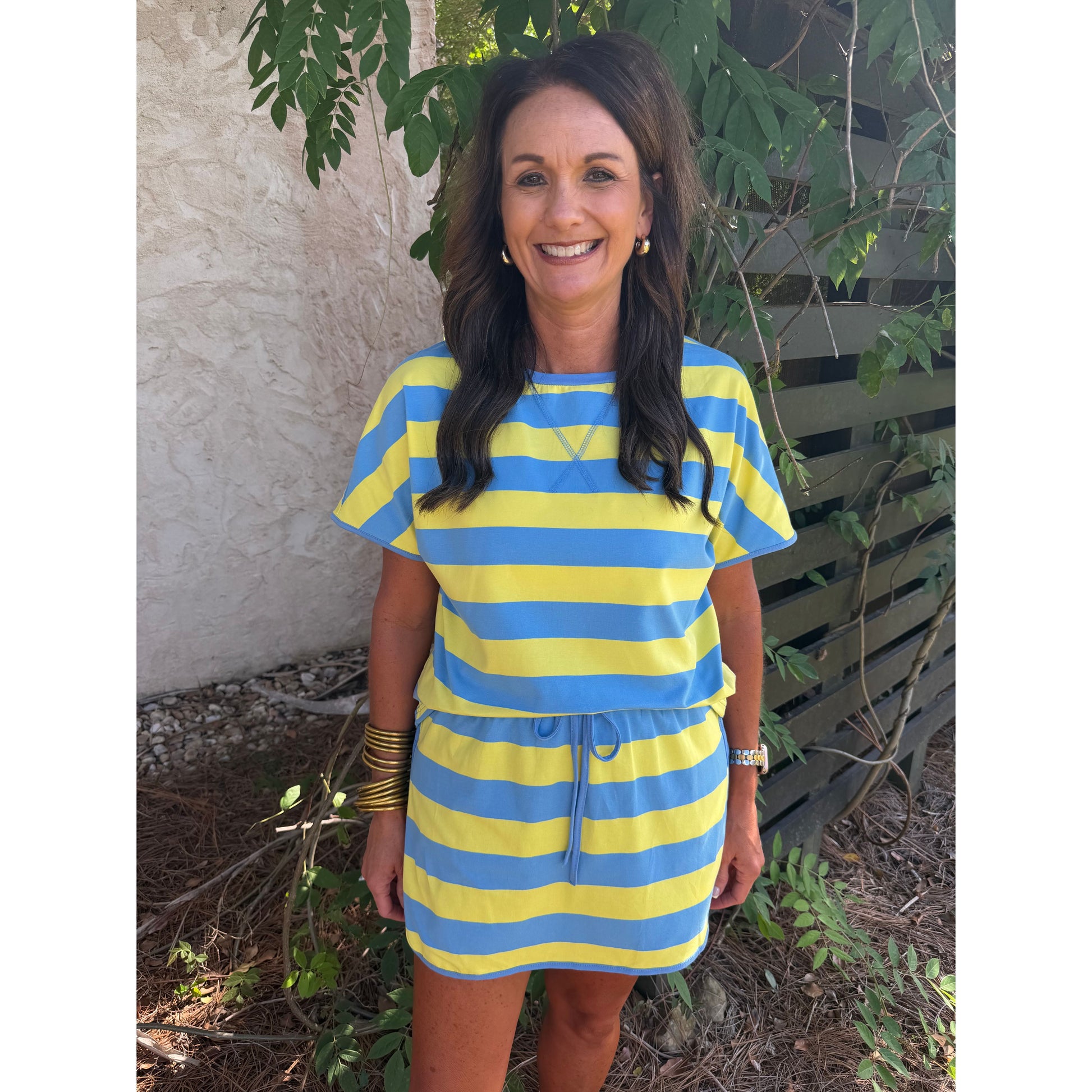 Woman wearing a blue and yellow striped dress standing outdoors.
