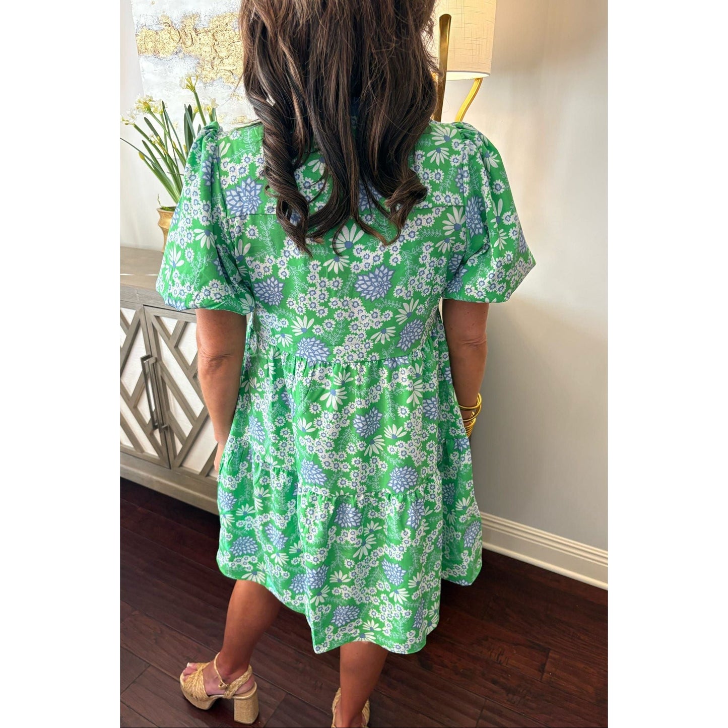 Person wearing a green floral dress in an indoor setting
