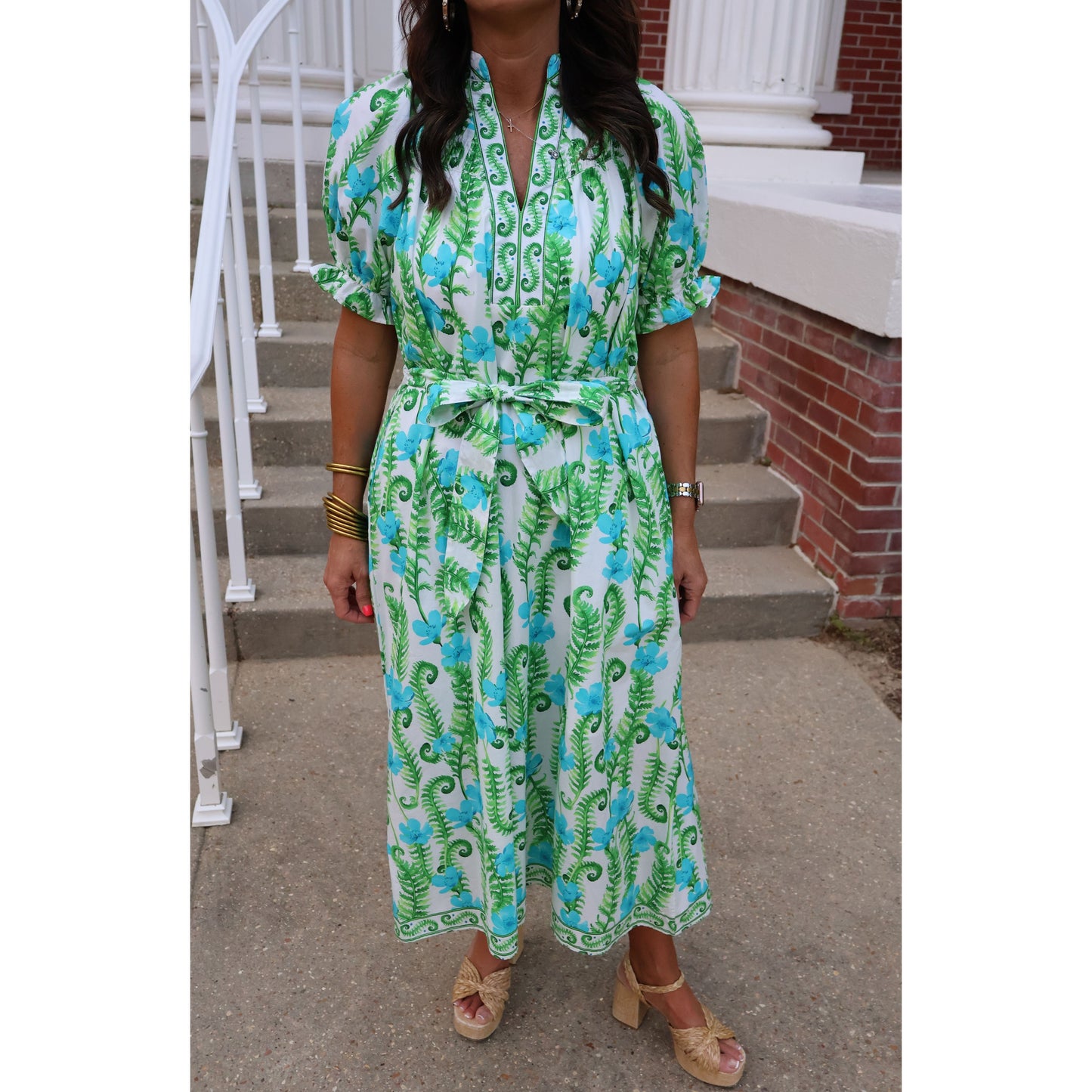 Person wearing a green and blue floral dress on a staircase.