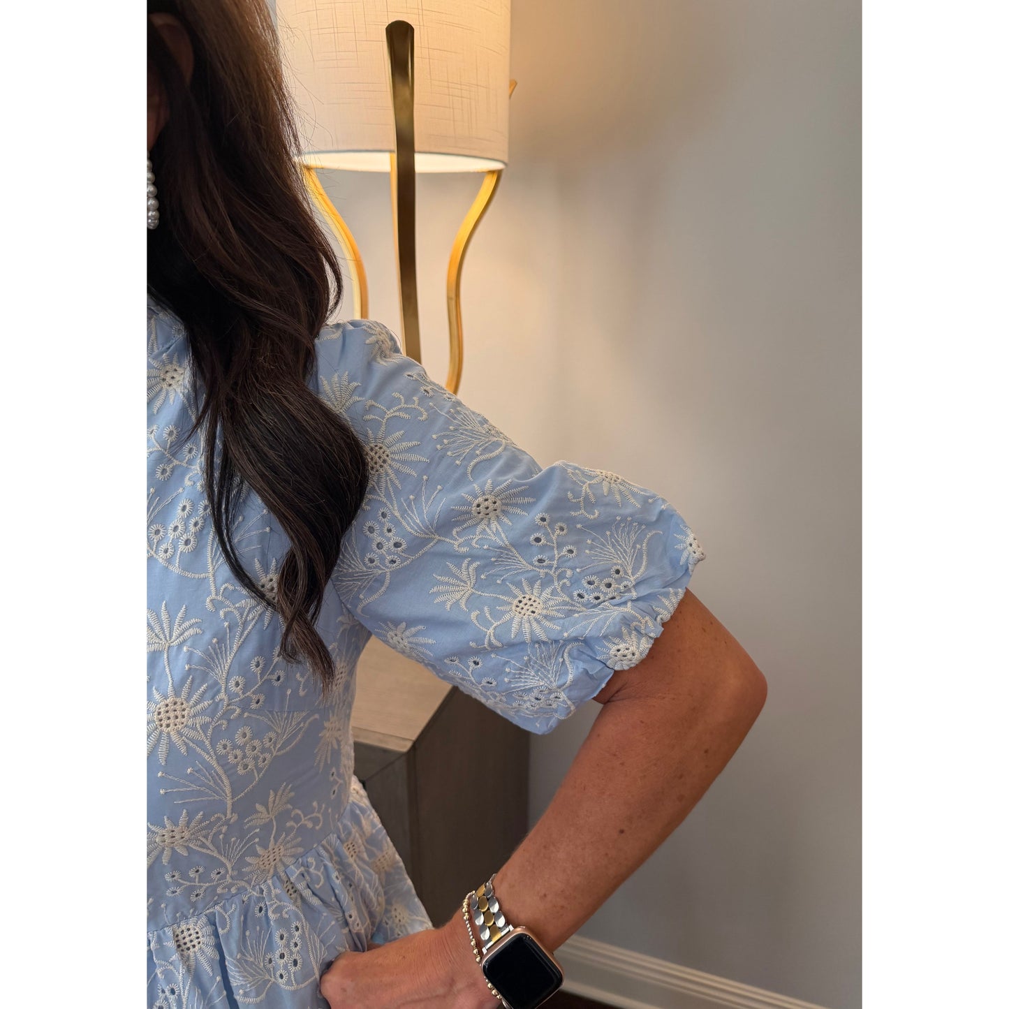 Person wearing blue floral pajama pants sitting on a bed with a lamp in the background.