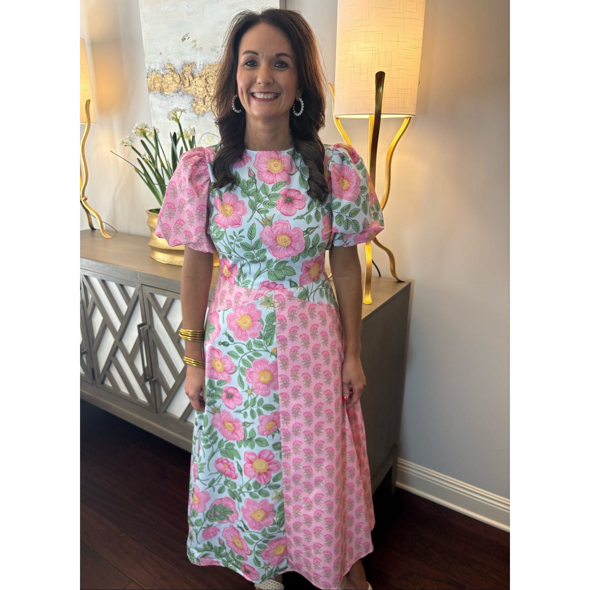 Woman wearing a floral dress in a room with lamps and decor.