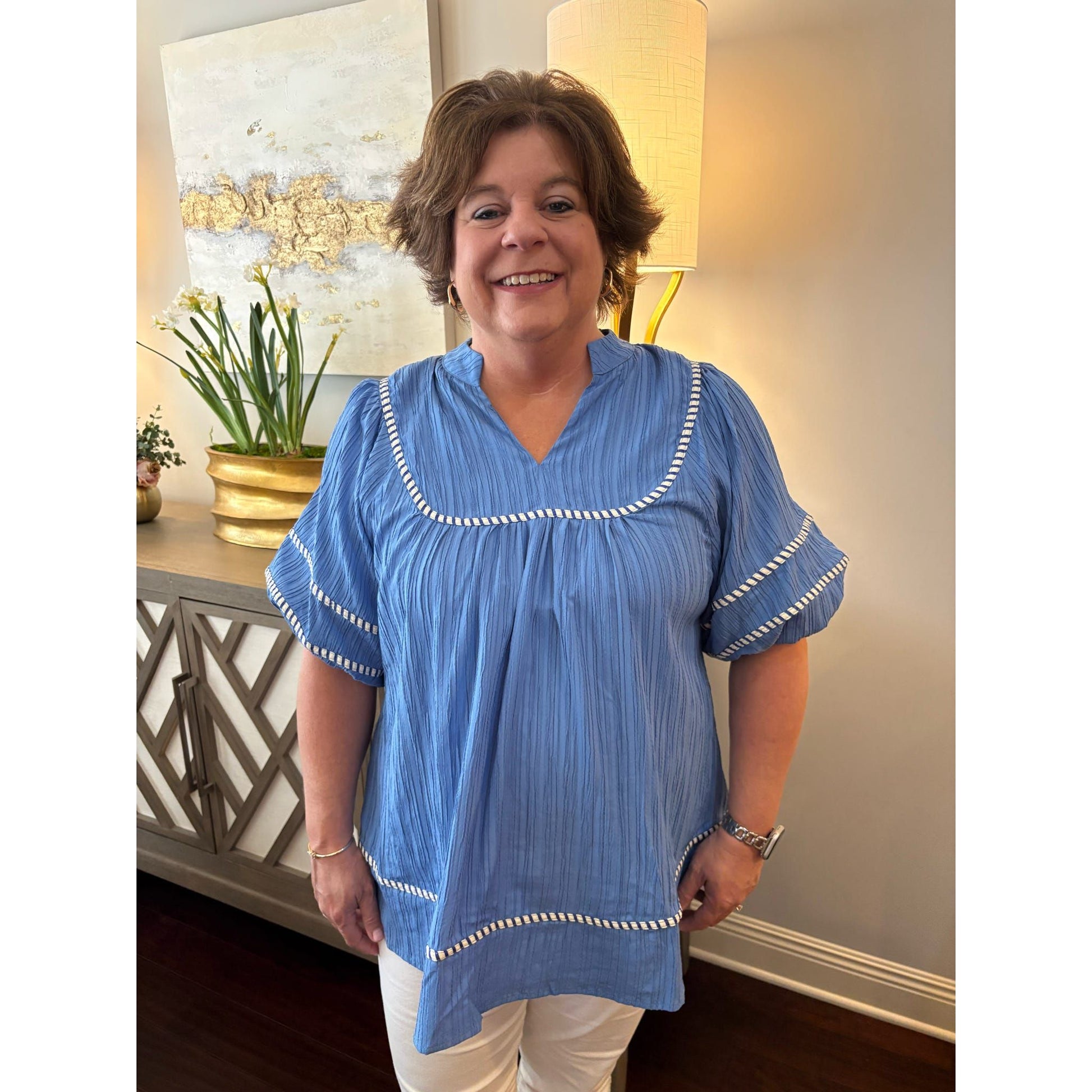Woman wearing a blue blouse with white trim in a home setting