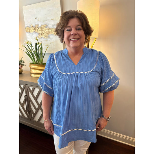 Woman wearing a blue blouse with white trim in a home setting