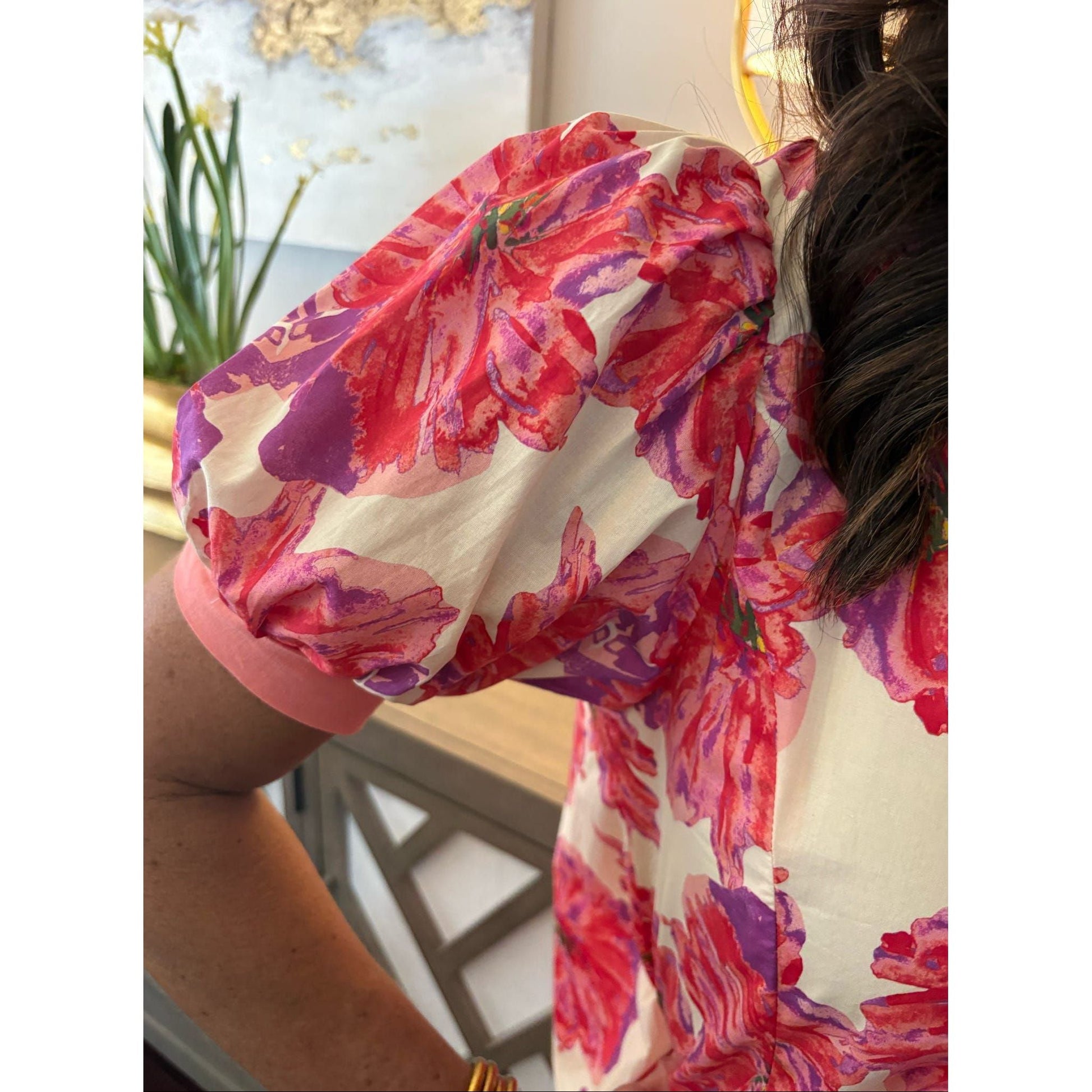 Person wearing a colorful floral dress with a blurred background