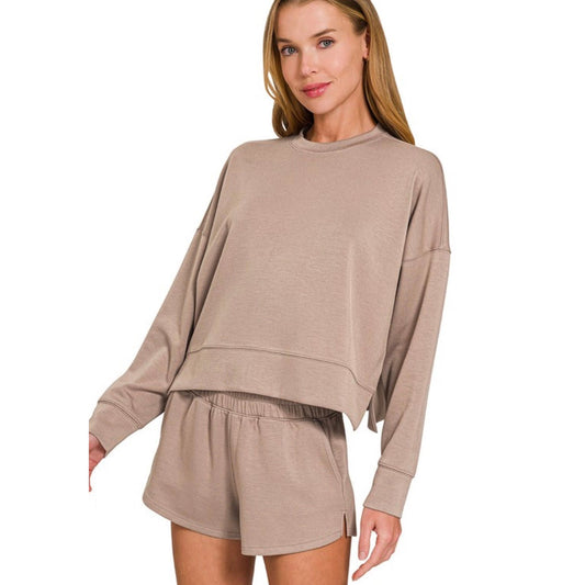 Woman wearing a beige long-sleeve top and shorts set on a white background