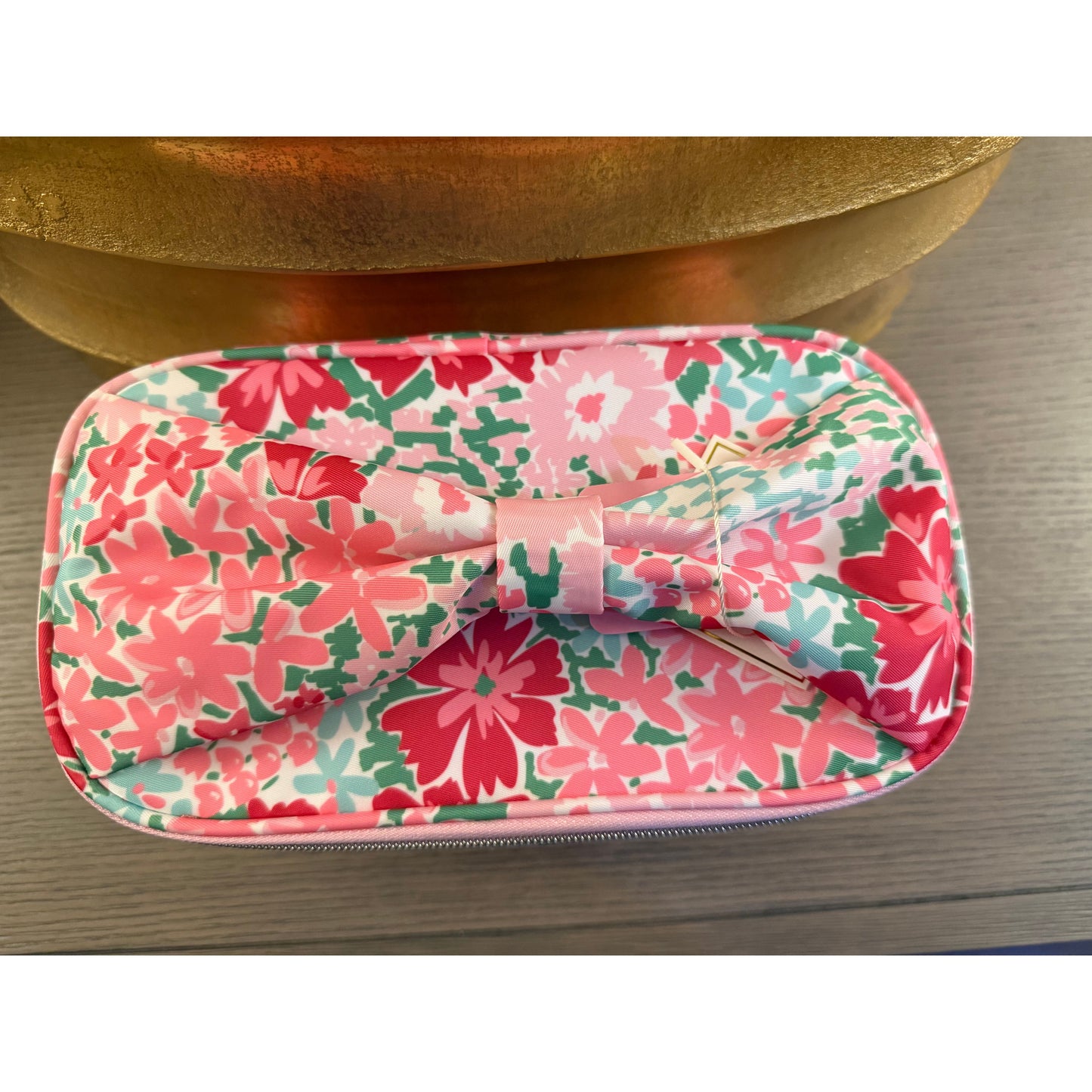 Floral-patterned pouch with a bow on a wooden surface