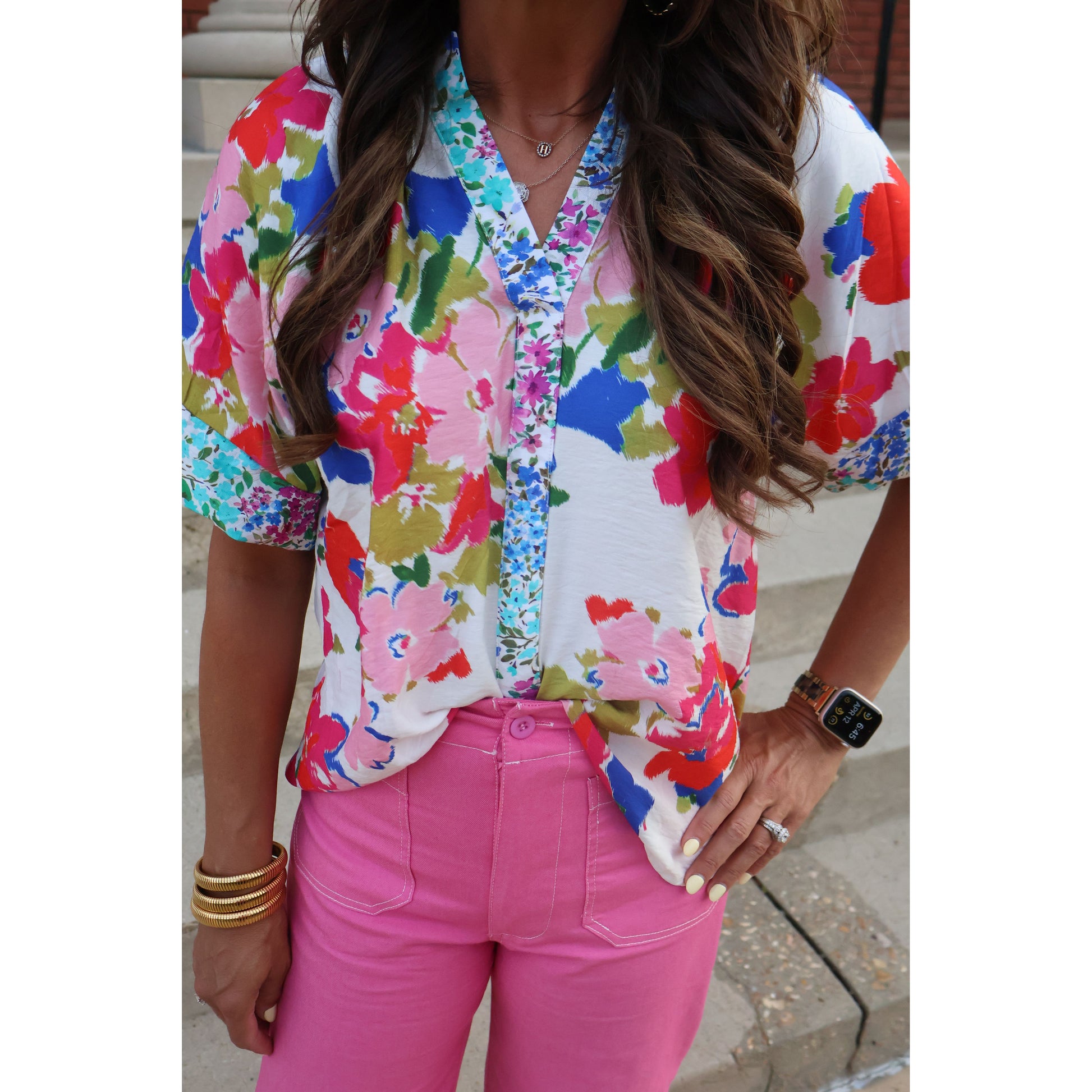 Person wearing a colorful floral dress with pink pants.