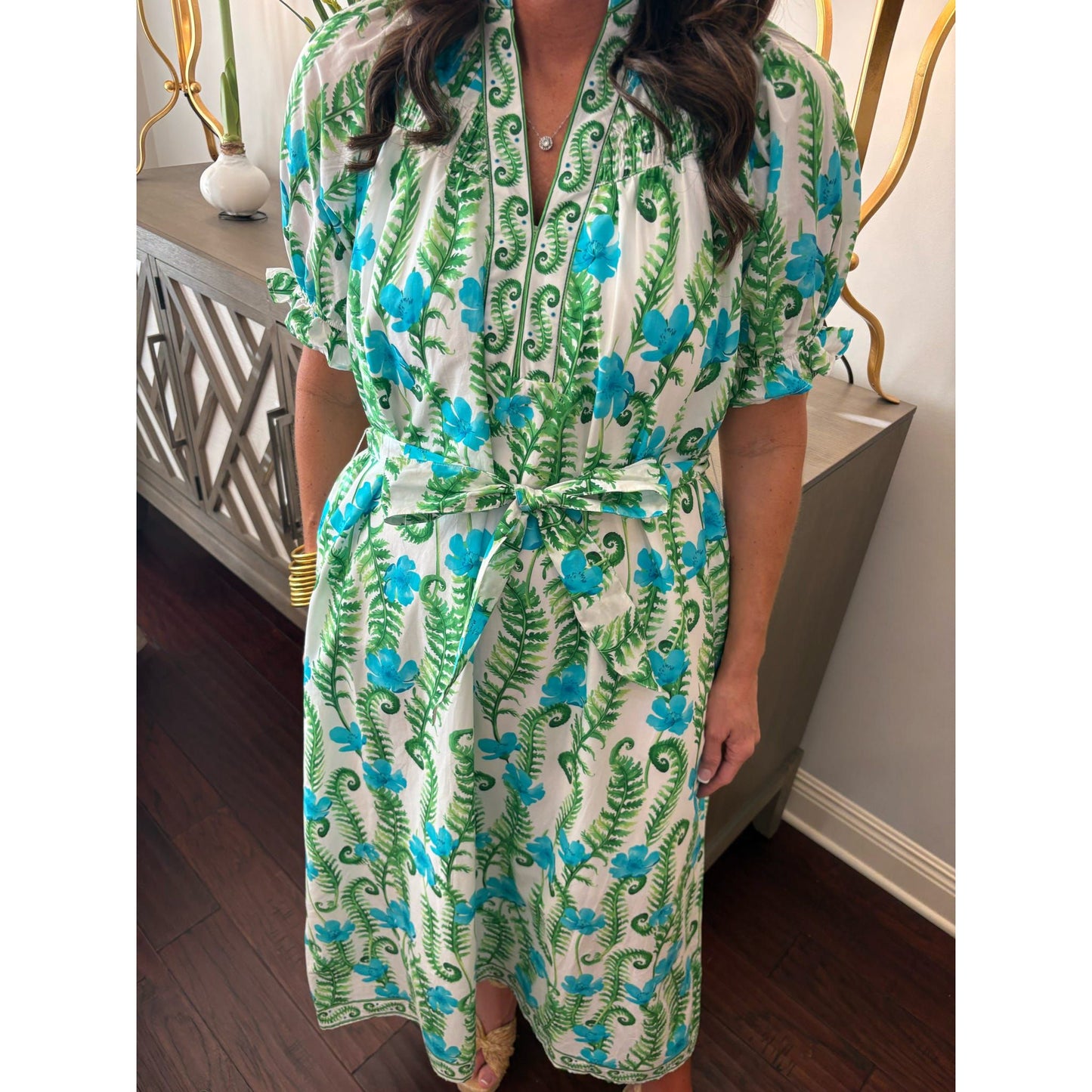 Person wearing a green and blue floral dress indoors.