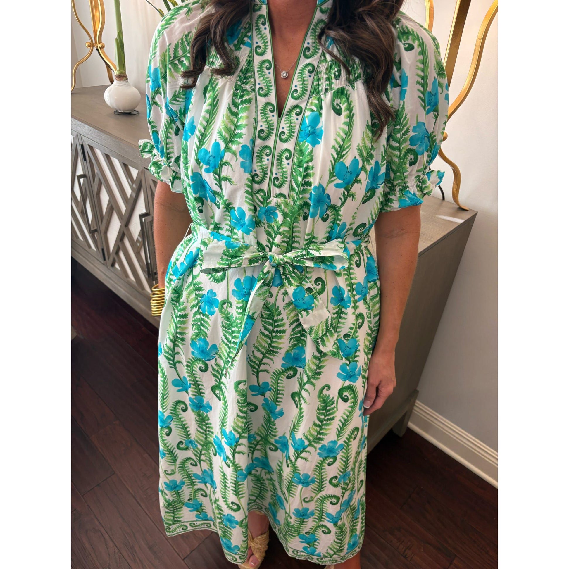 Person wearing a green and blue floral dress indoors.