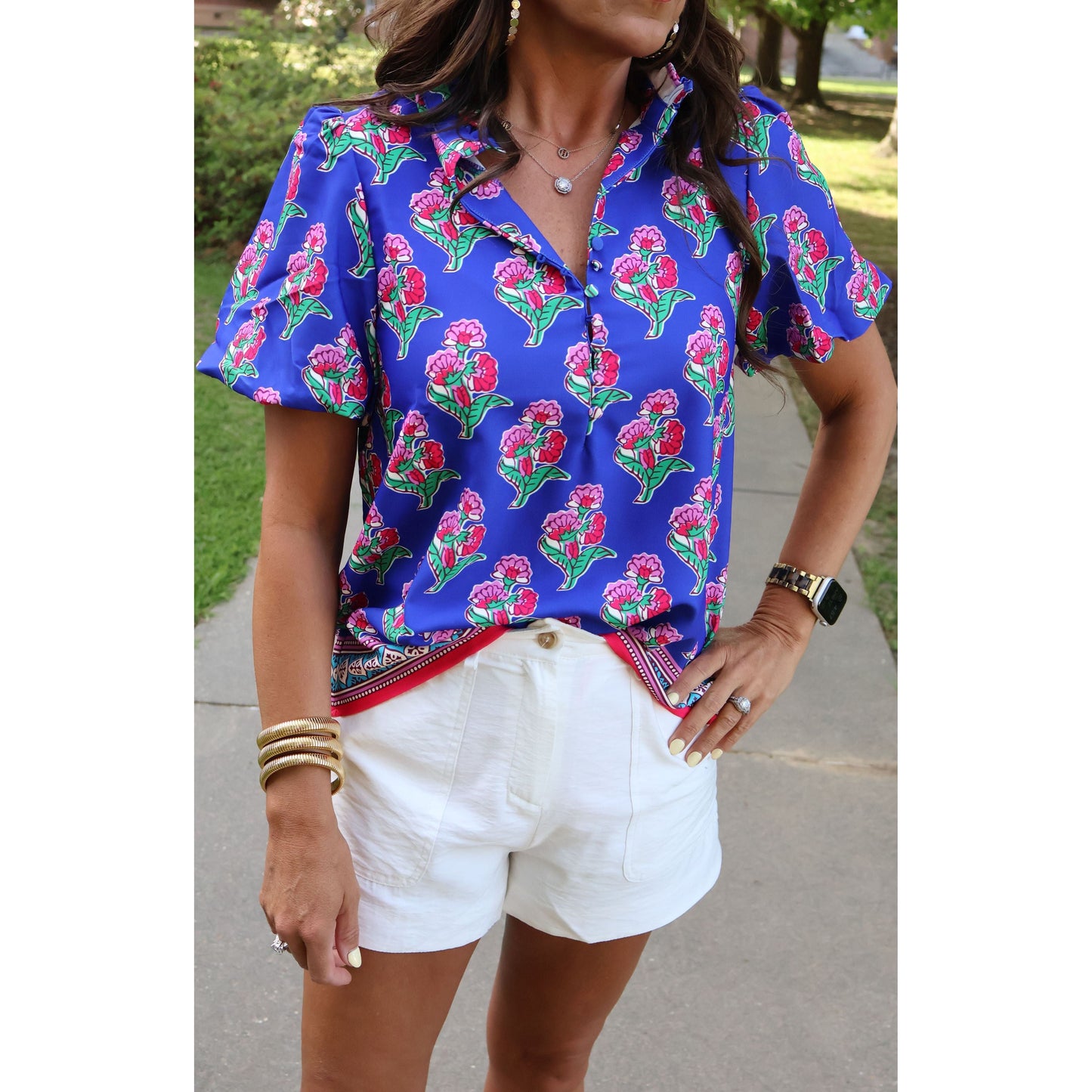 Person wearing a colorful floral dress with white shorts outdoors.