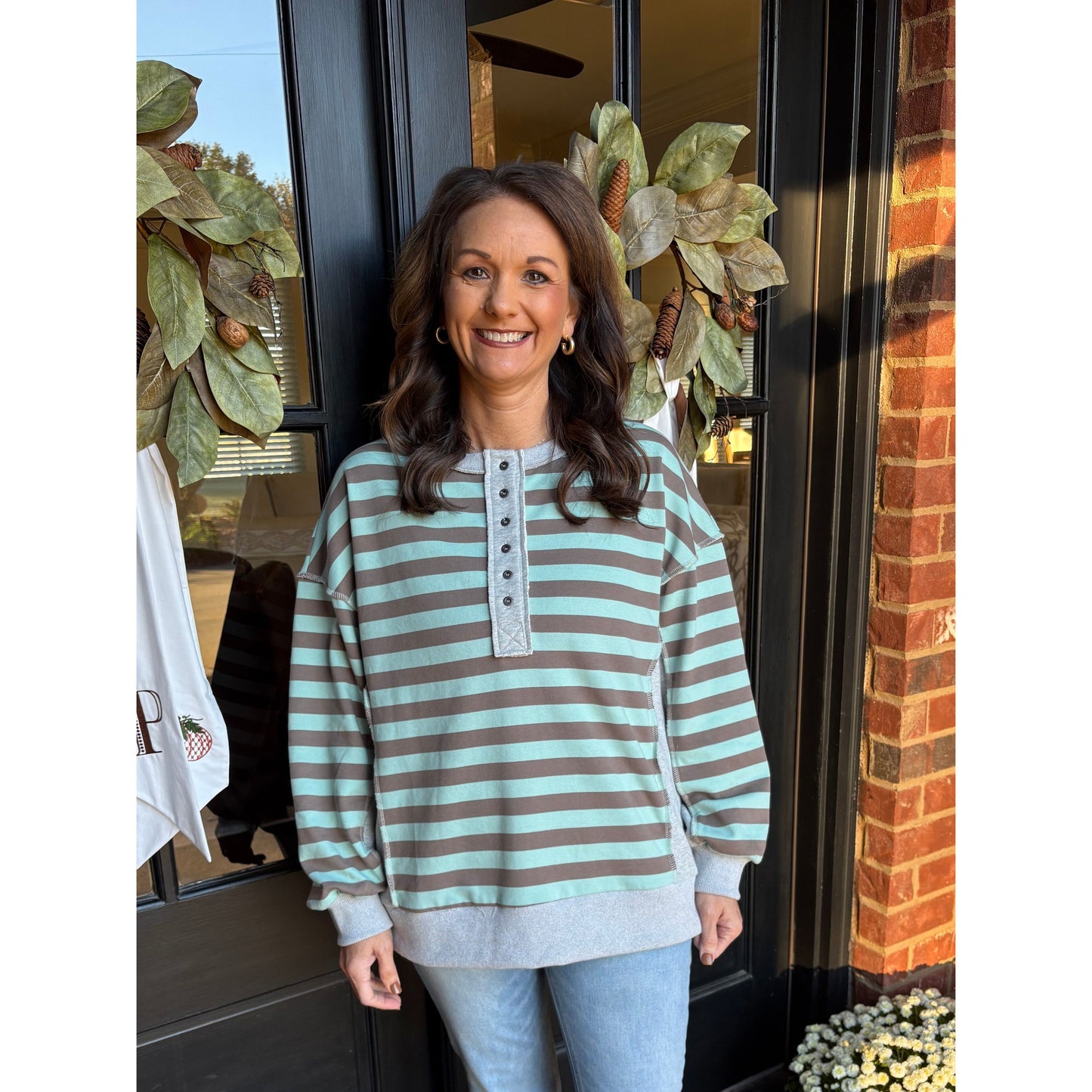 Woman standing in front of a door with decorative plants and flowers.