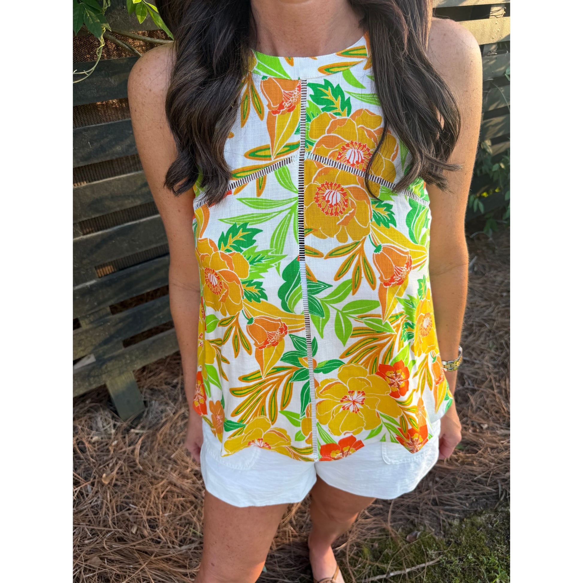 Person wearing a colorful floral dress with a wooden fence background