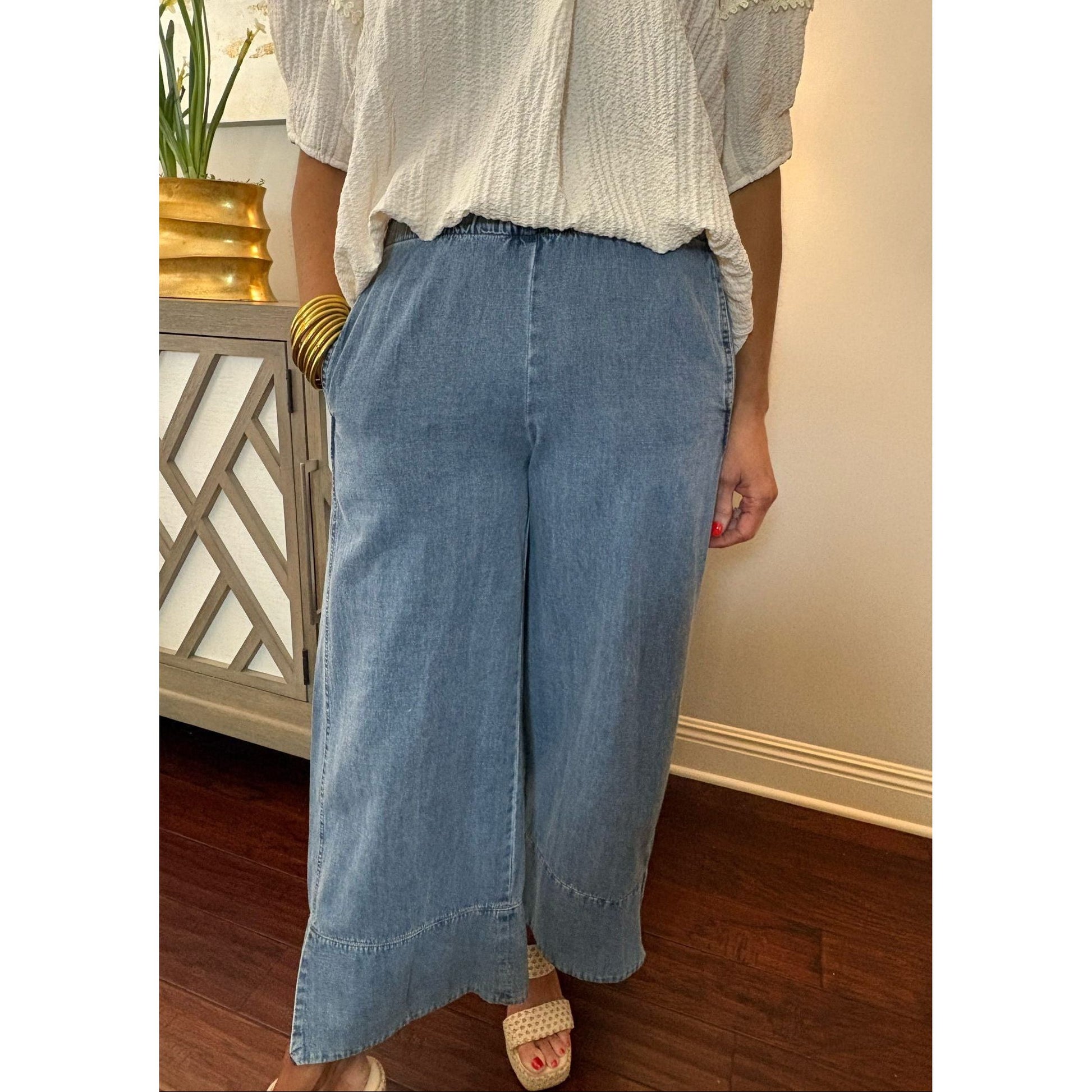 Person wearing a white blouse and blue jeans indoors.