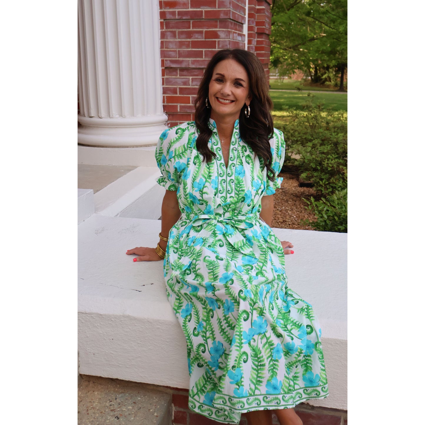 Woman wearing a green and blue floral dress standing outdoors.
