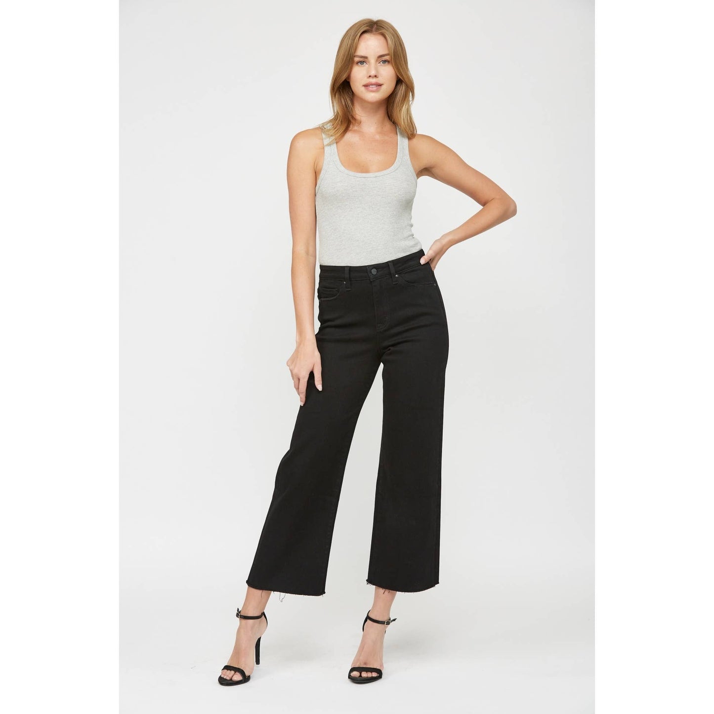 Woman wearing a white tank top and black wide-leg jeans on a white background