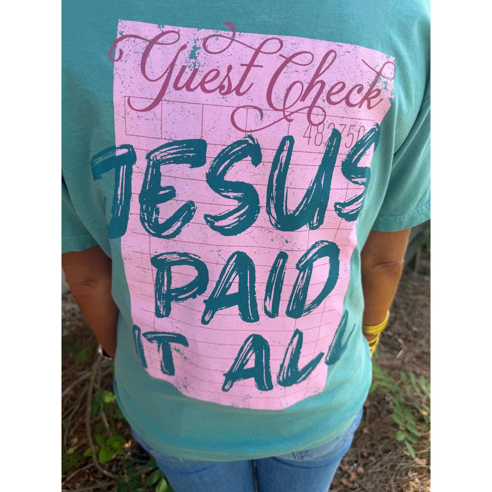 Person holding a pink sign with text in a natural setting