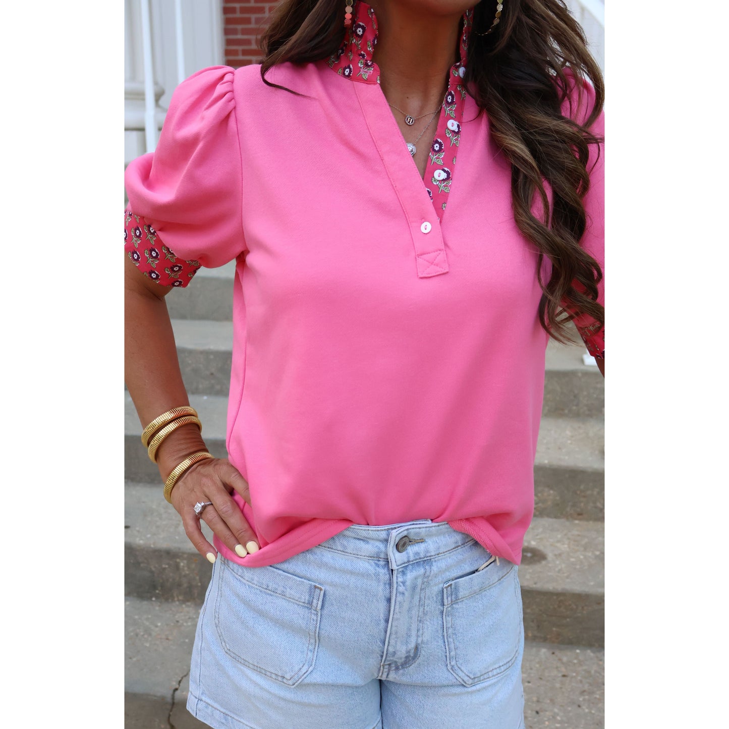 Person wearing a pink hoodie and light blue jeans with a blurred background