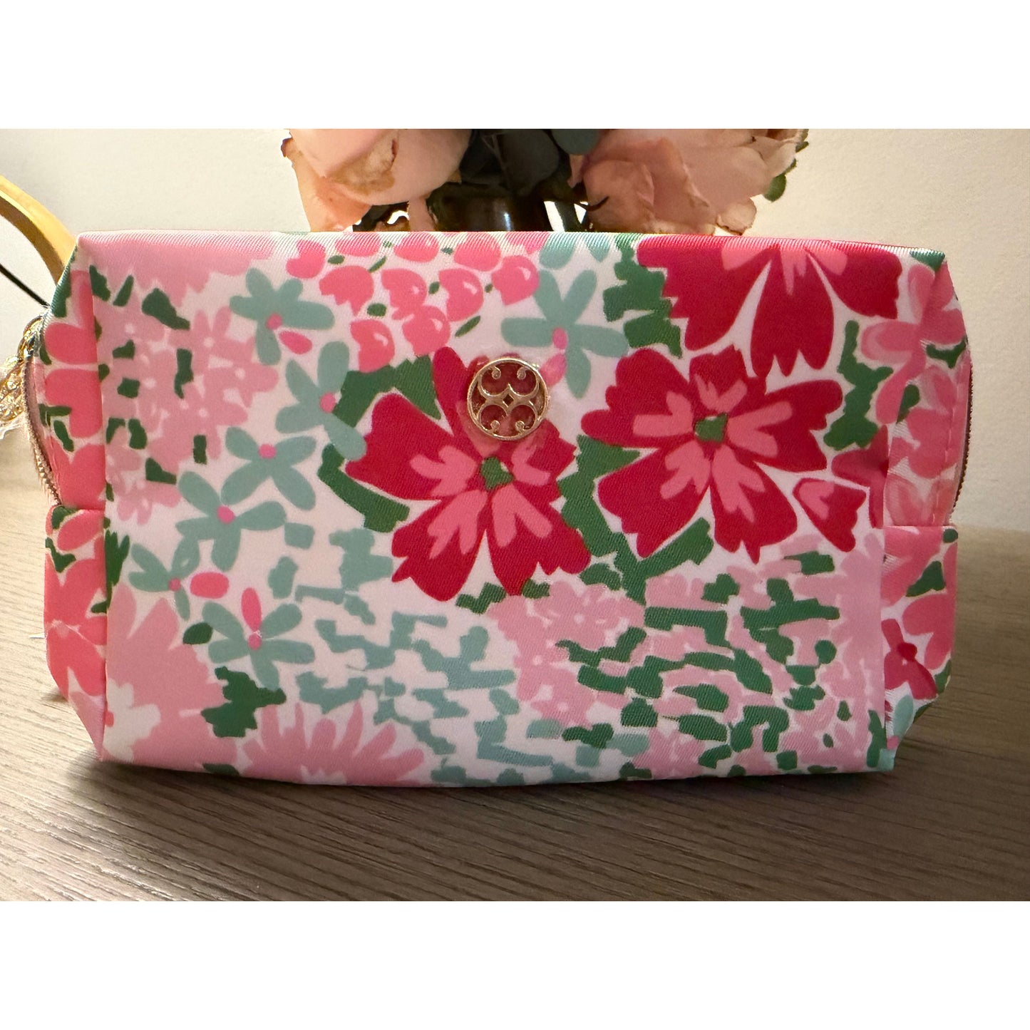 Floral-patterned pouch with a brand logo on a wooden surface