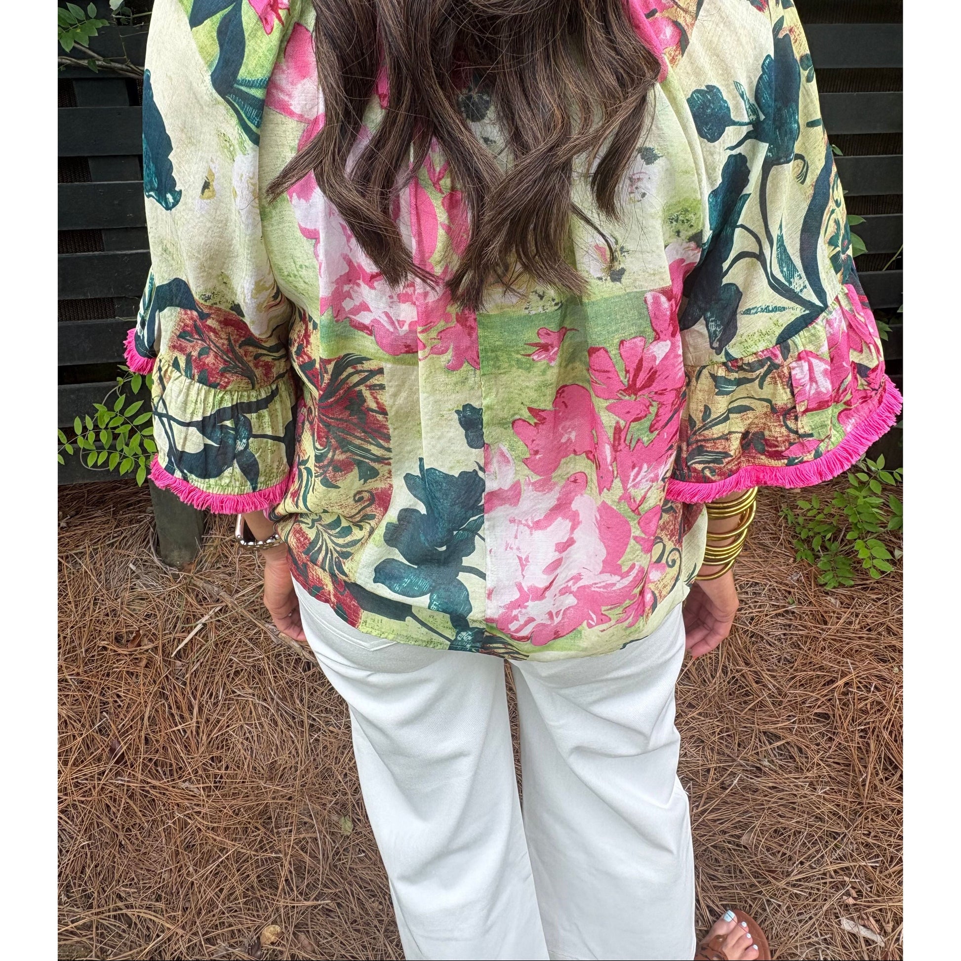 Person wearing a colorful floral jacket with a pattern of pink, green, and black flowers.